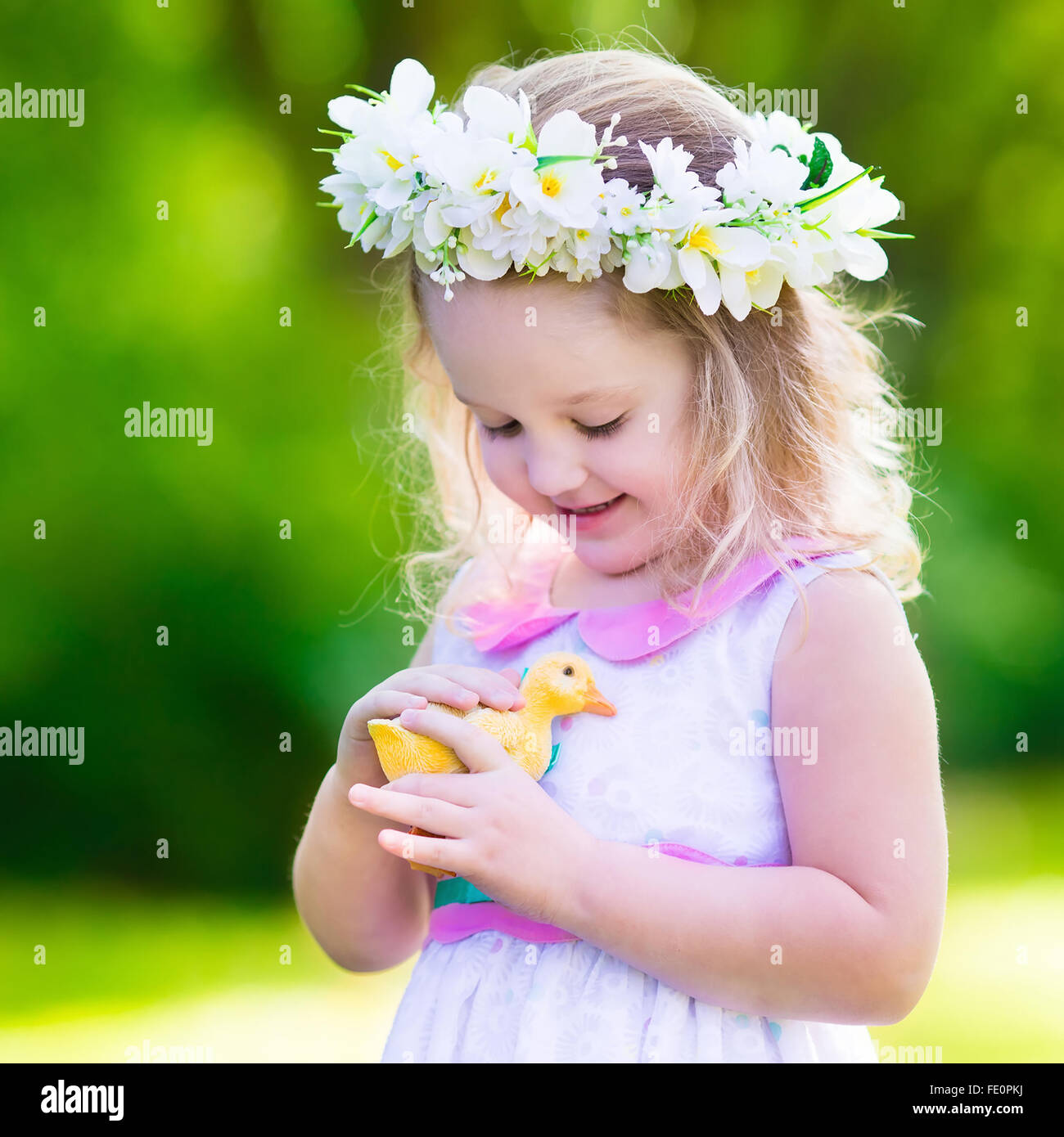 Kleines Mädchen Spaß auf Ostereiersuche. Kid im Blume Krone spielen mit Spielzeug Ente oder Huhn. Kinder, die auf der Suche nach Eiern Stockfoto