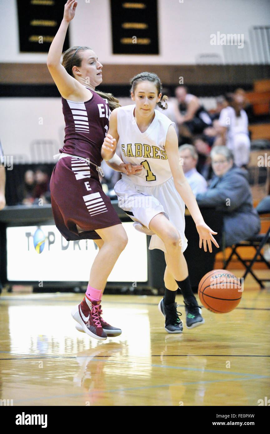 Ein High School Spieler setzt den Ball auf den Boden und beginnt mit einer Fahrt auf den Korb unter enger defensiven Druck. USA. Stockfoto