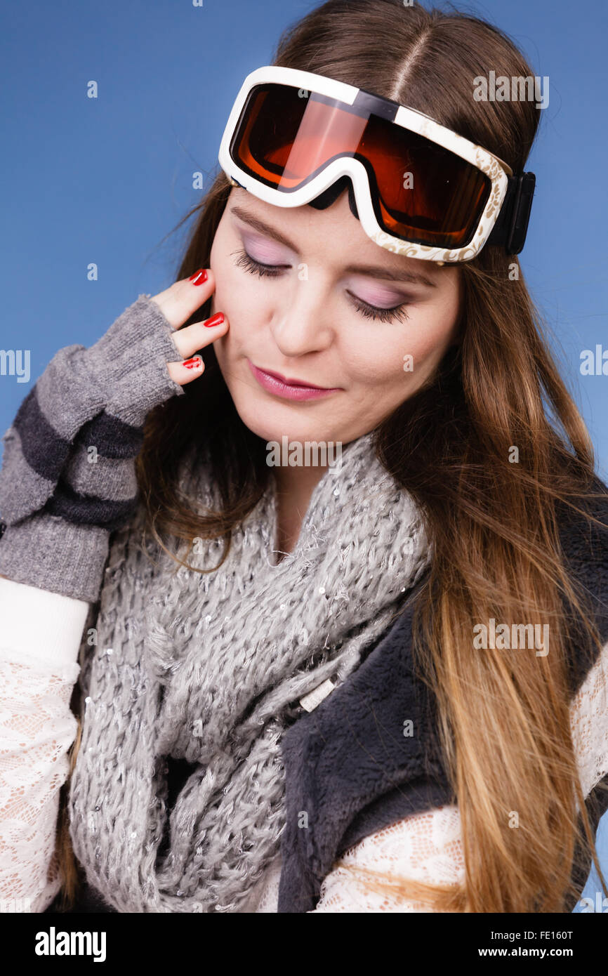 Woman Skifahrer Mädchen tragen warme Kleidung Ski Googles Porträt. Winter Sportaktivität. Schöne Sportlerin auf blauen Studioaufnahme Stockfoto