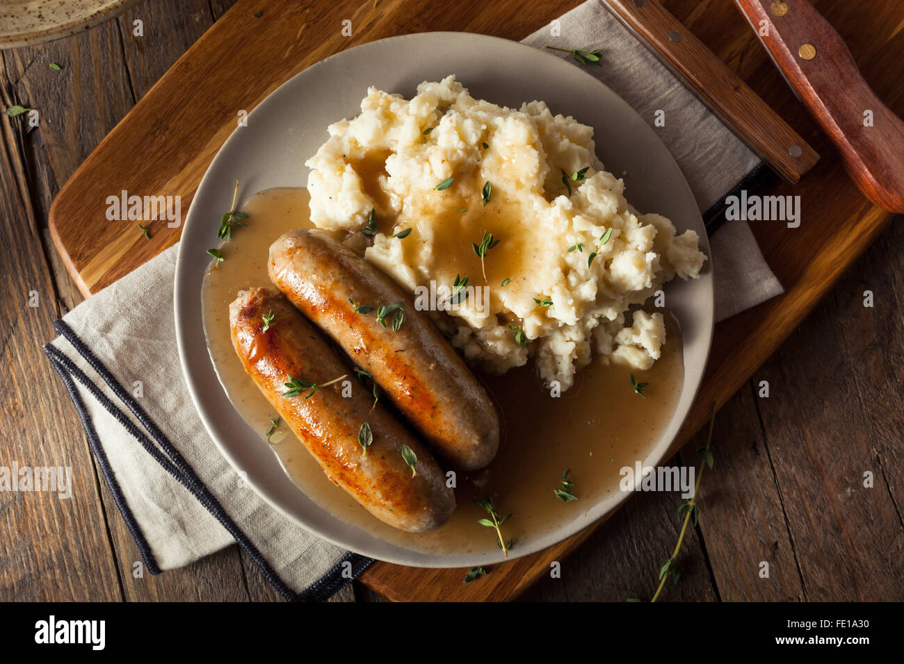 Hausgemachte Bangers and Mash mit Kräutern und Soße Stockfoto