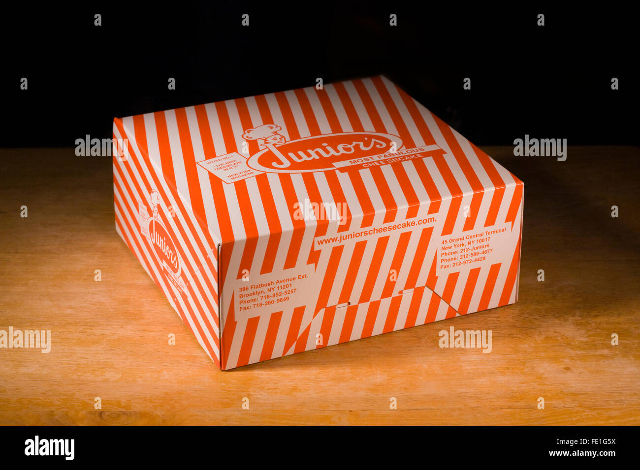 Eine ikonische Orange gestreift Juniors Käsekuchen Box aus Brooklyn Flaggschiff Restaurant in New York City auf einer hölzernen Tischplatte Stockfoto