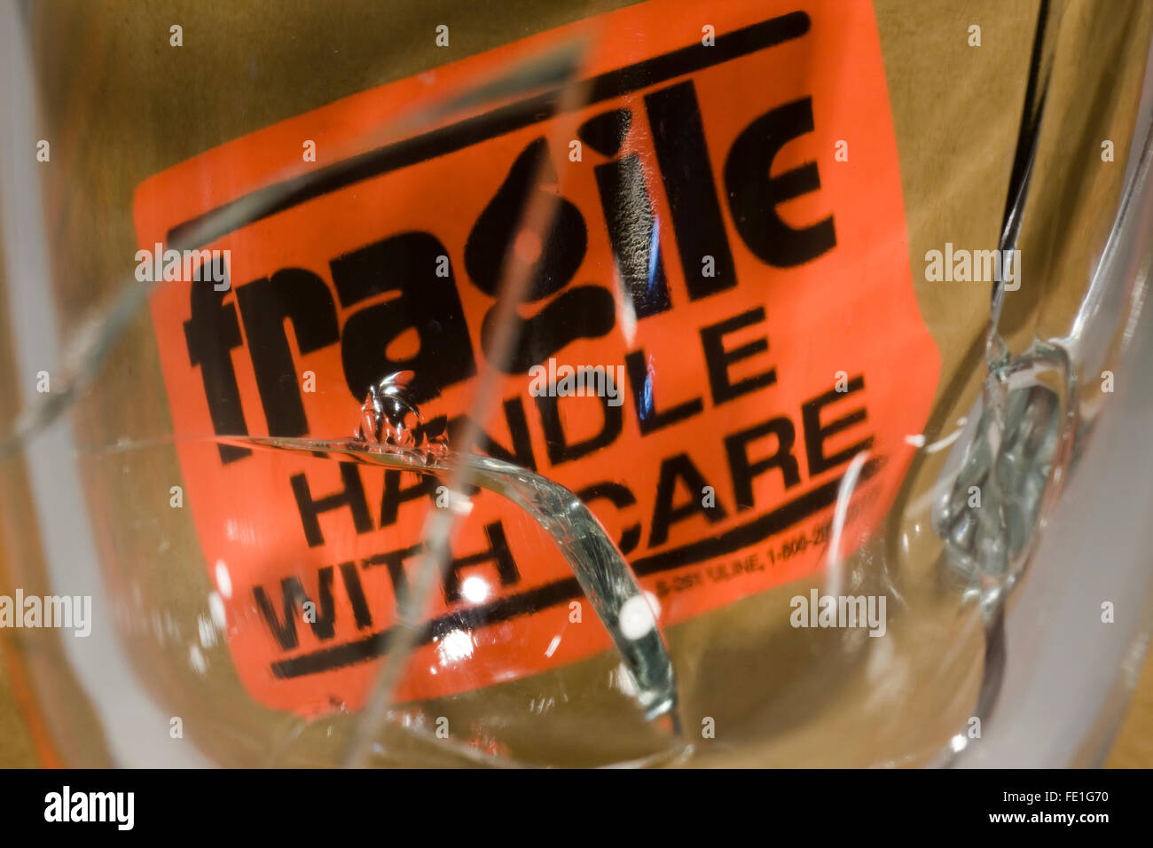 Melden Sie grossen Riss im Glas vor einer Orange "Fragile Handle With Care" Stockfoto