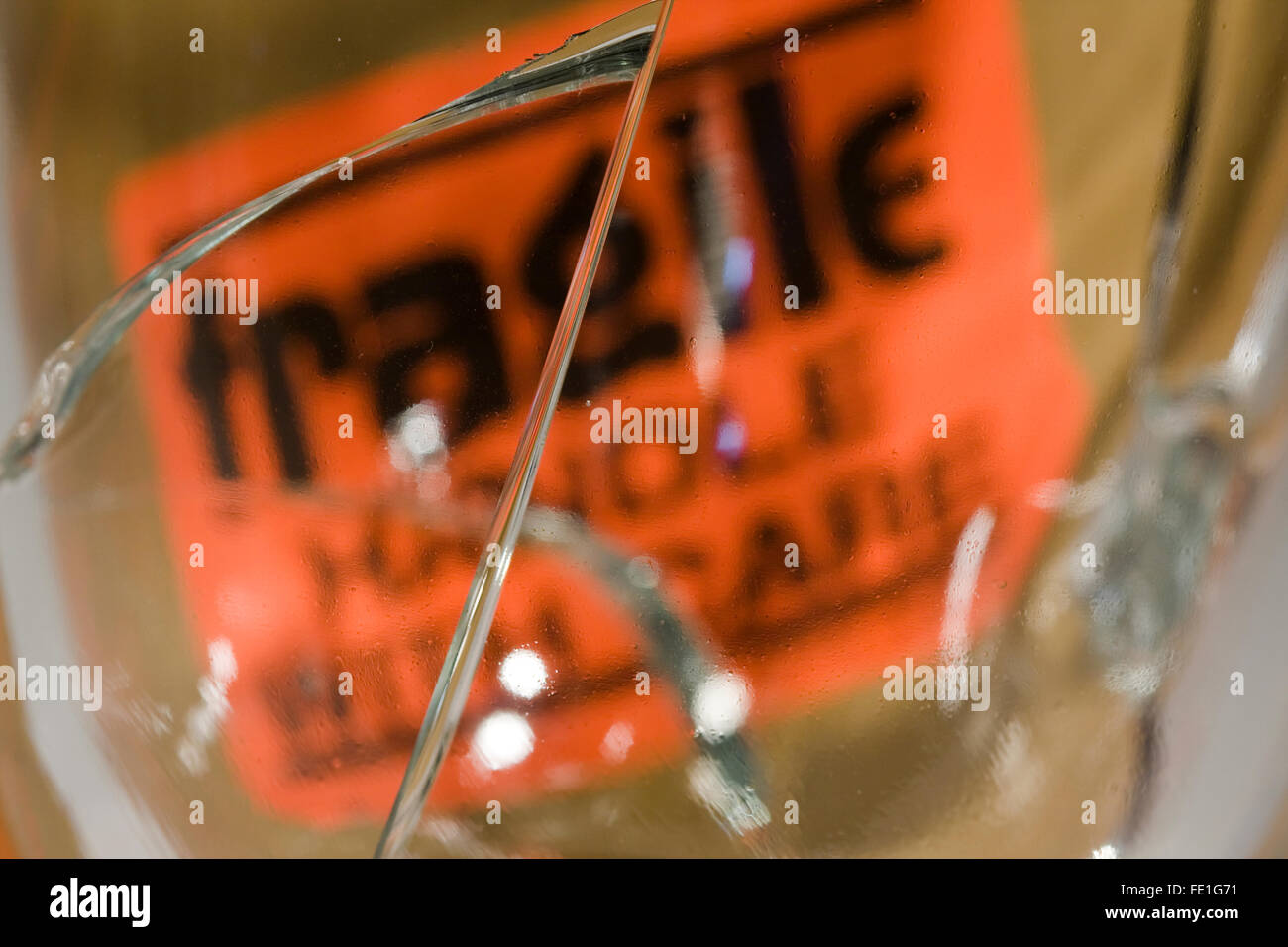 Melden Sie grossen Riss im Glas vor einer Orange "Fragile Handle With Care" Stockfoto