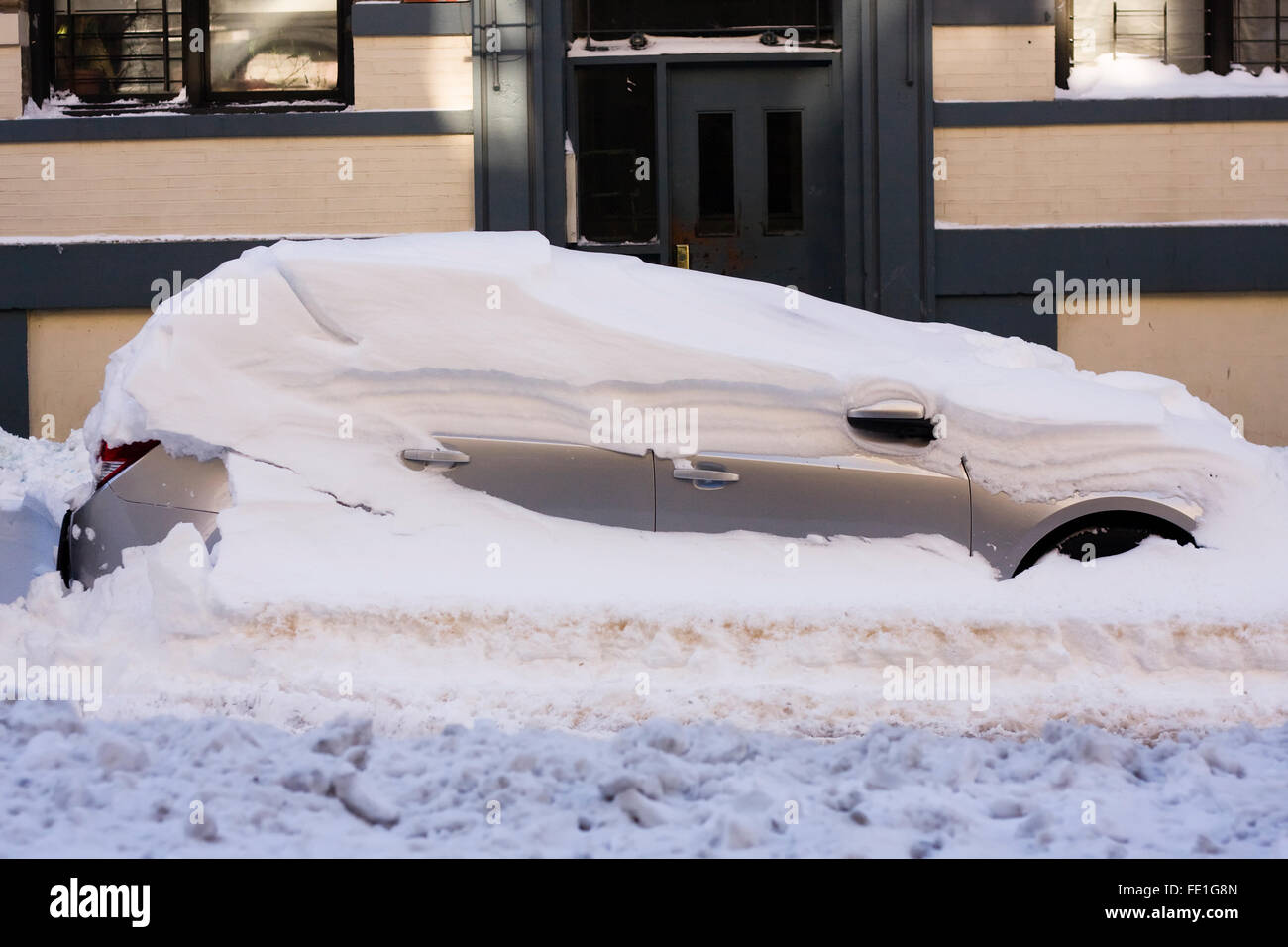 Eine schneebedeckte Fahrzeug noch auf einer Stadtstraße ausgegraben werden, nachdem ein Übernachtung Schneesturm Blizzard Bedingungen es begraben Stockfoto