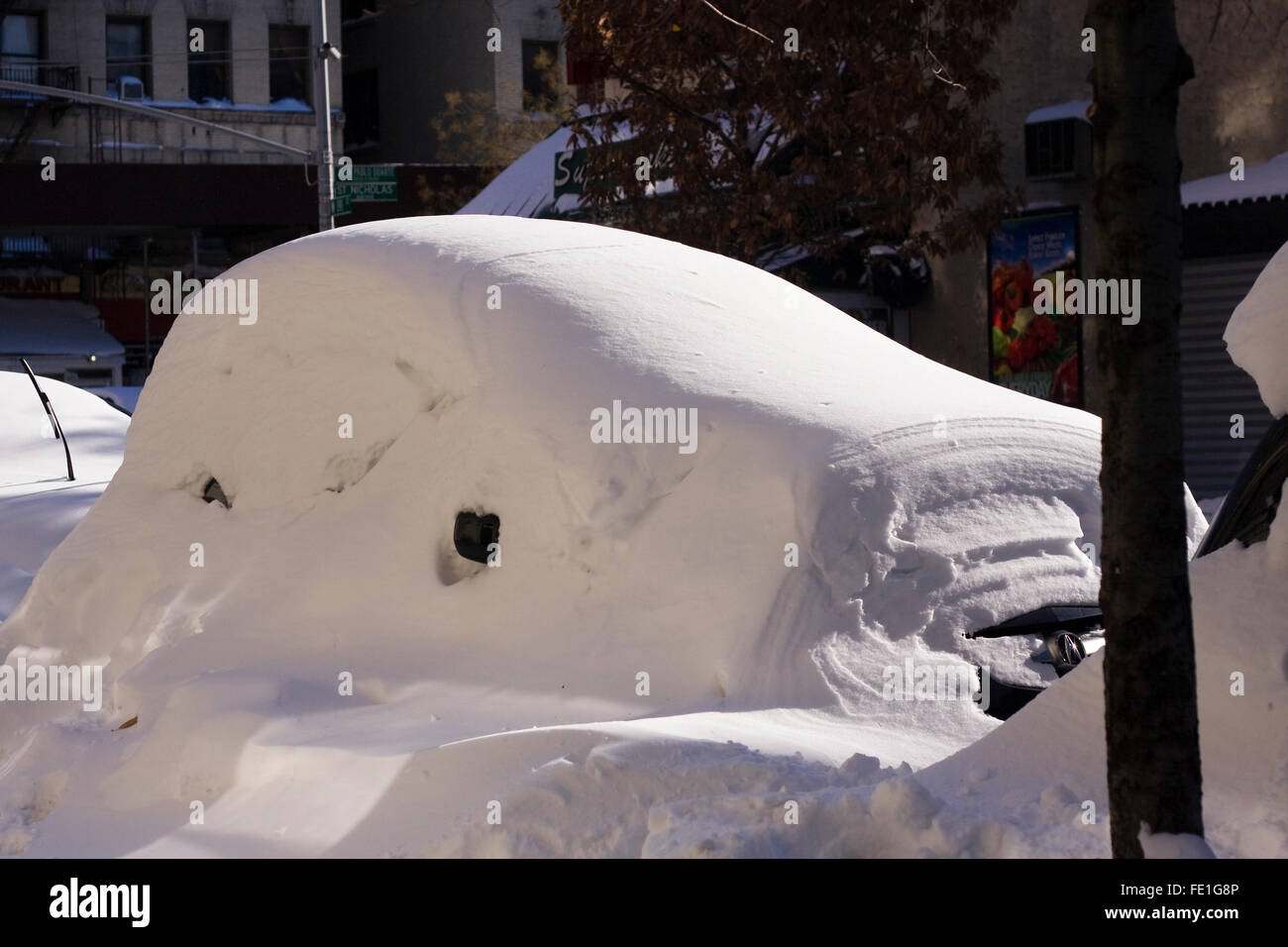Eine schneebedeckte Fahrzeug noch auf einer Stadtstraße ausgegraben werden, nachdem ein Übernachtung Schneesturm Blizzard Bedingungen es begraben Stockfoto