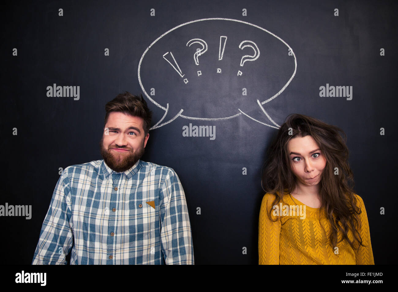 Hässliche junge Paar scherzen und Grimassieren über Tafel Hintergrund Stockfoto