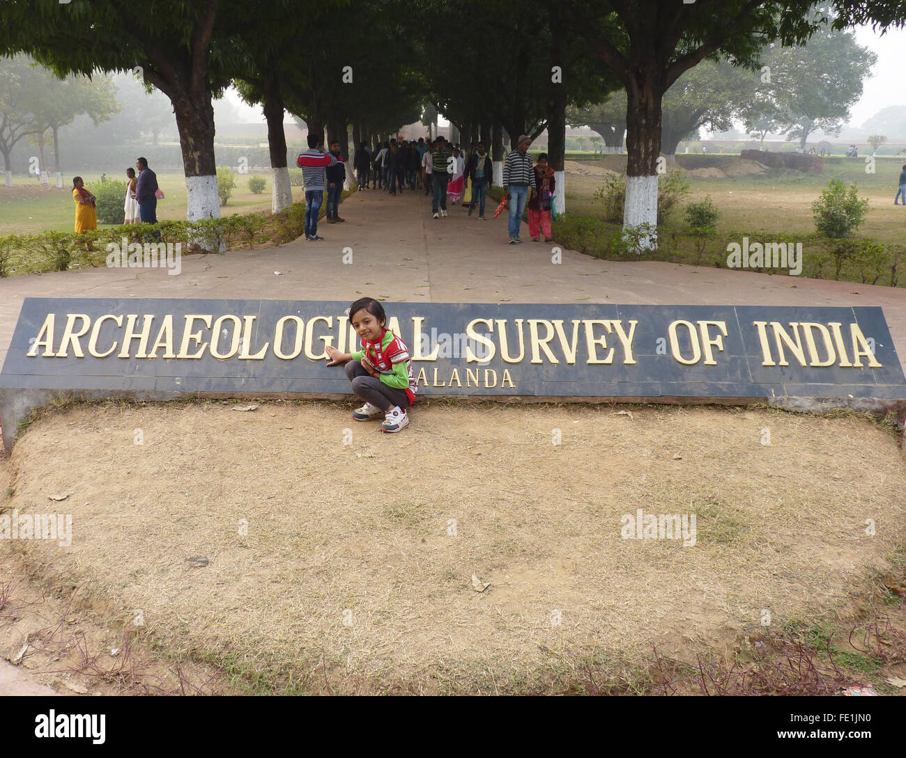 Ein kleines Mädchen zeigt auf das Schild des Archaeological Survey of India an der Ausgrabungsstätte von Universität von Nalanda Stockfoto