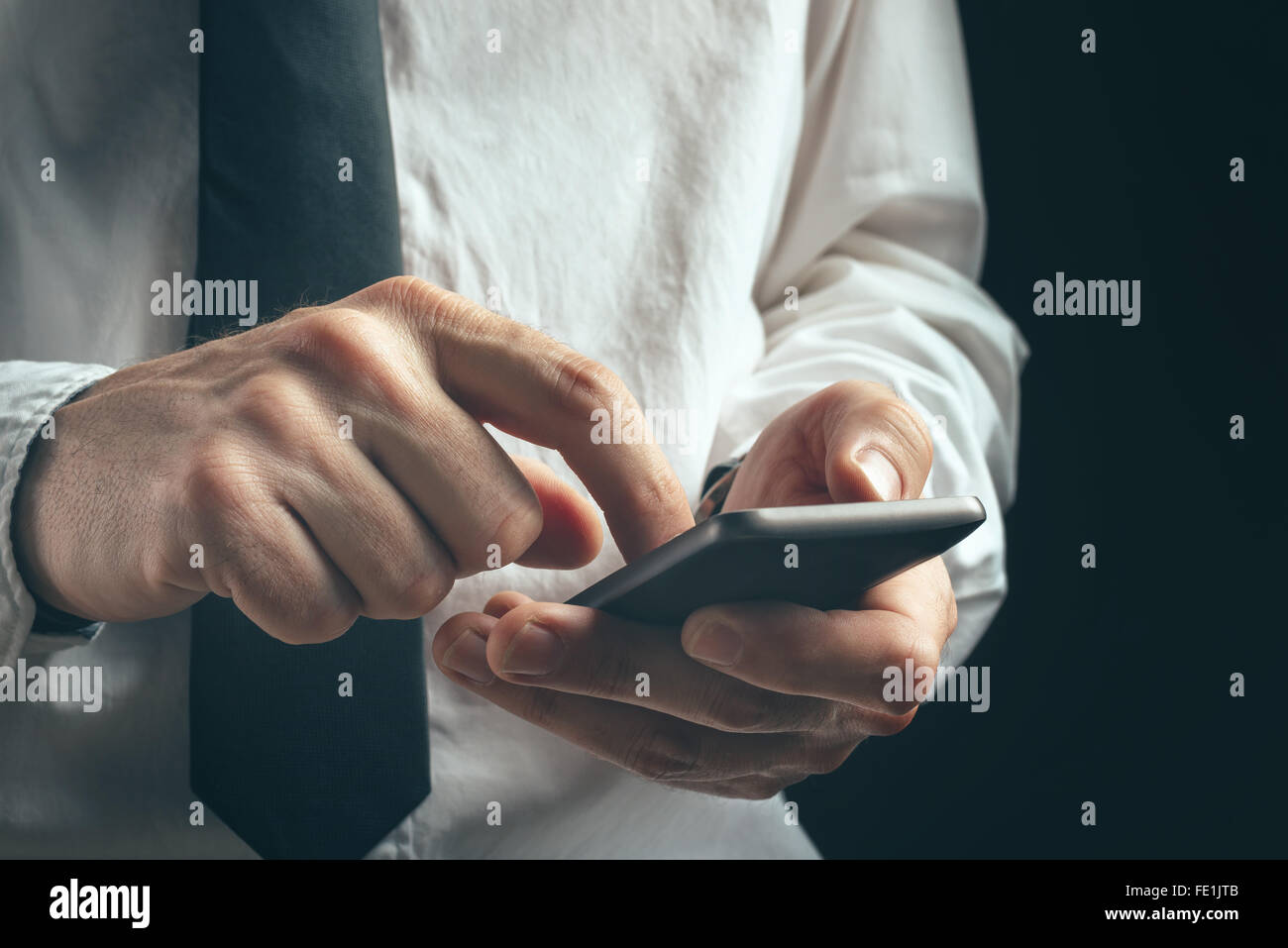 Jungunternehmer unkenntlich professionelle SMS auf Smartphone mit Nachricht app in dunklen Büroeinrichtung. Stockfoto