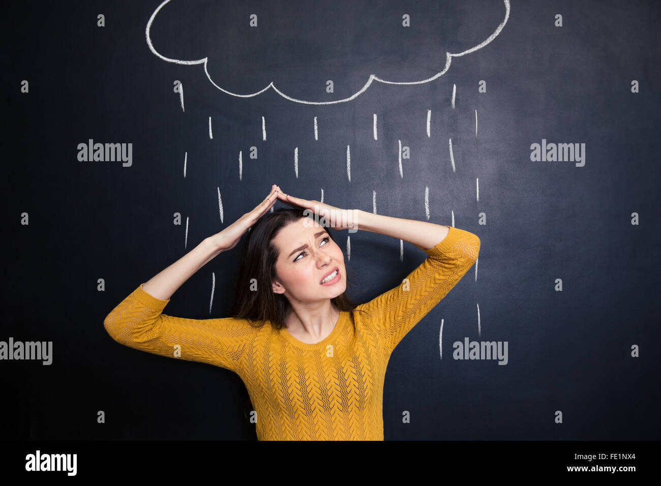 Verärgert junge Frau über den Kopf mit Händen von Regen auf Hintergrund der Tafel gezeichnet Stockfoto
