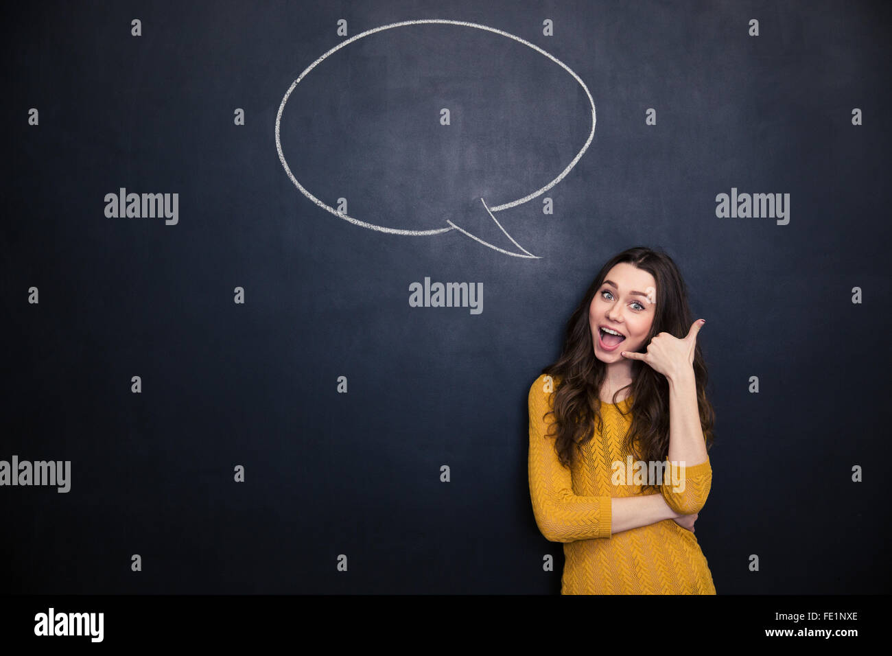 Gerne schöne junge Frau gestikulieren telefonieren und auf Tafel Hintergrund mit leere Sprechblase stehen Stockfoto