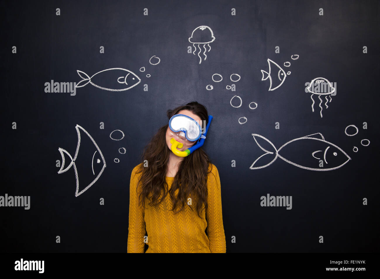 Hübsche junge Frau in Taucherbrille und Schnorchel über Tafel Hintergrund mit gezeichneten Unterwasserwelt posiert Stockfoto
