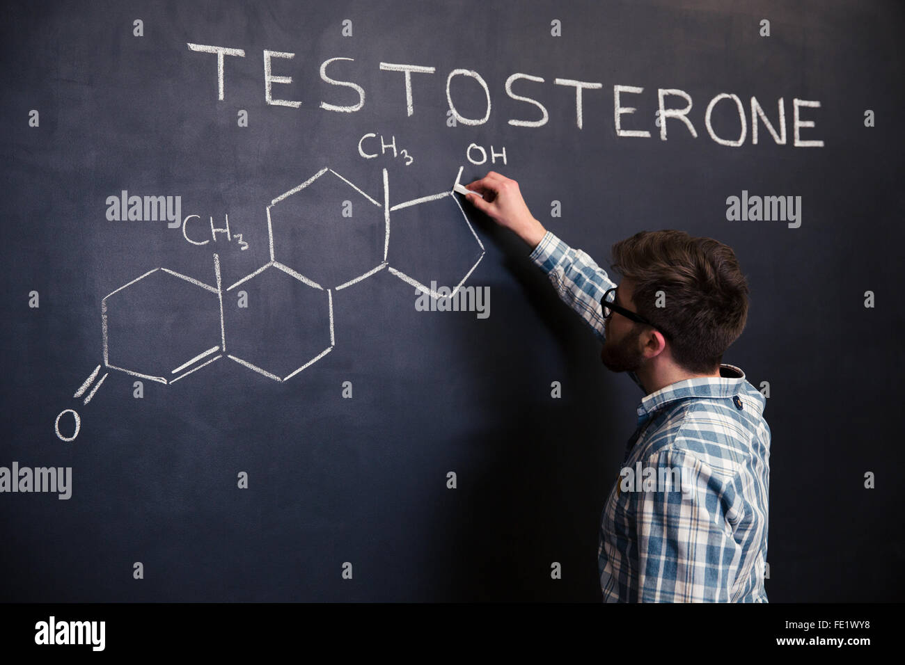 Jungen Student konzentriert in Gläser zeichnen chemischen Struktur von Testosteron-Molekül auf Tafel Stockfoto