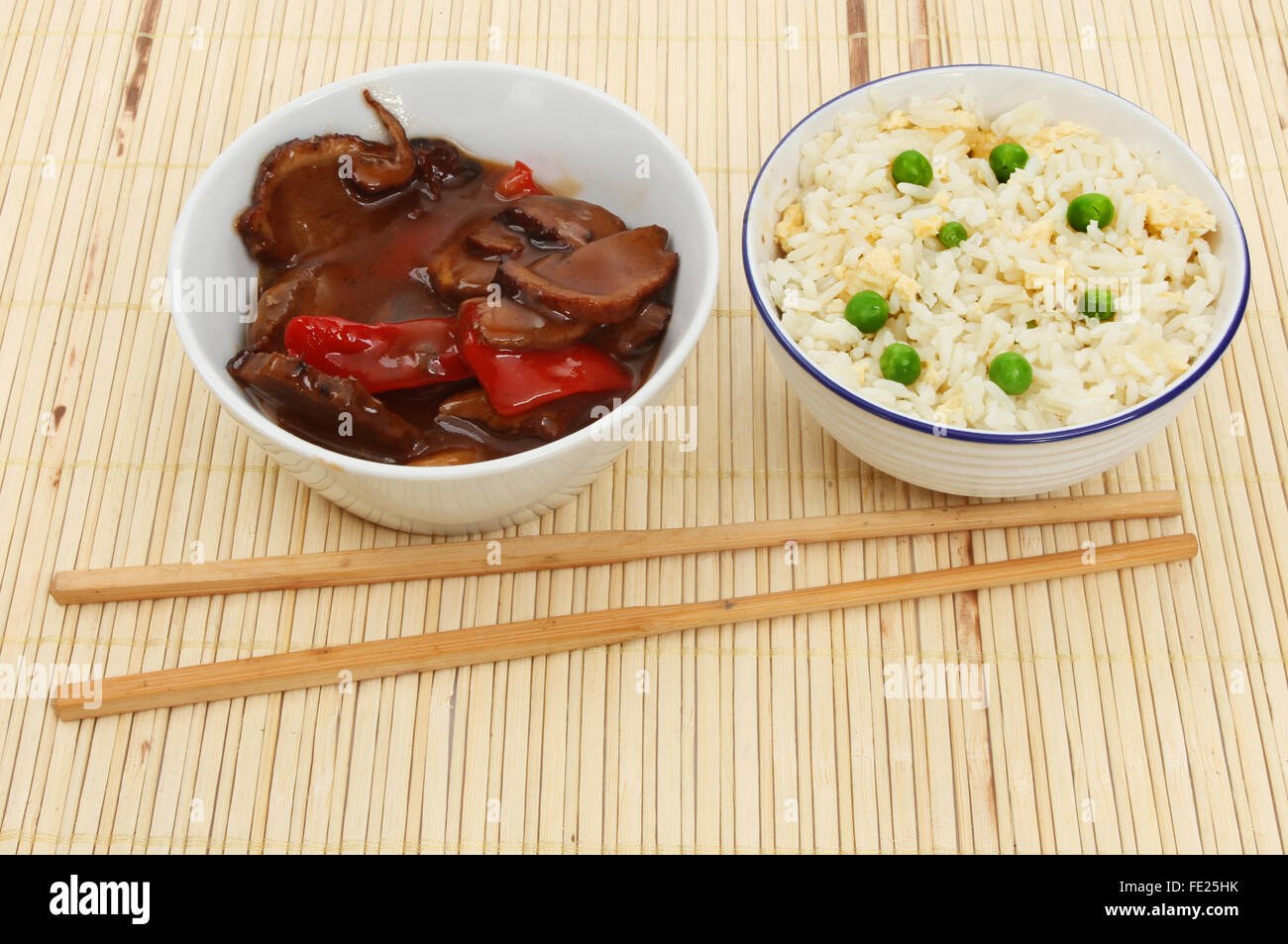 Chinesisches Essen, Ente in Pflaumensauce und Ei gebratenen Reis in Schalen mit Stäbchen auf eine Bambus-Matte Stockfoto