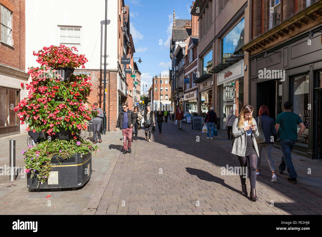 Person auf der Suche nach Handy während des Gehens, die von anderen Leuten auf einer belebten Straße der Stadt, Bridlesmith Tor, Nottingham, England, Großbritannien Stockfoto