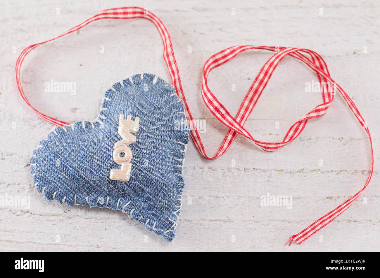 Denim-Herz mit dem Wort Liebe drauf gelegt auf eine hölzerne Tafel Stockfoto
