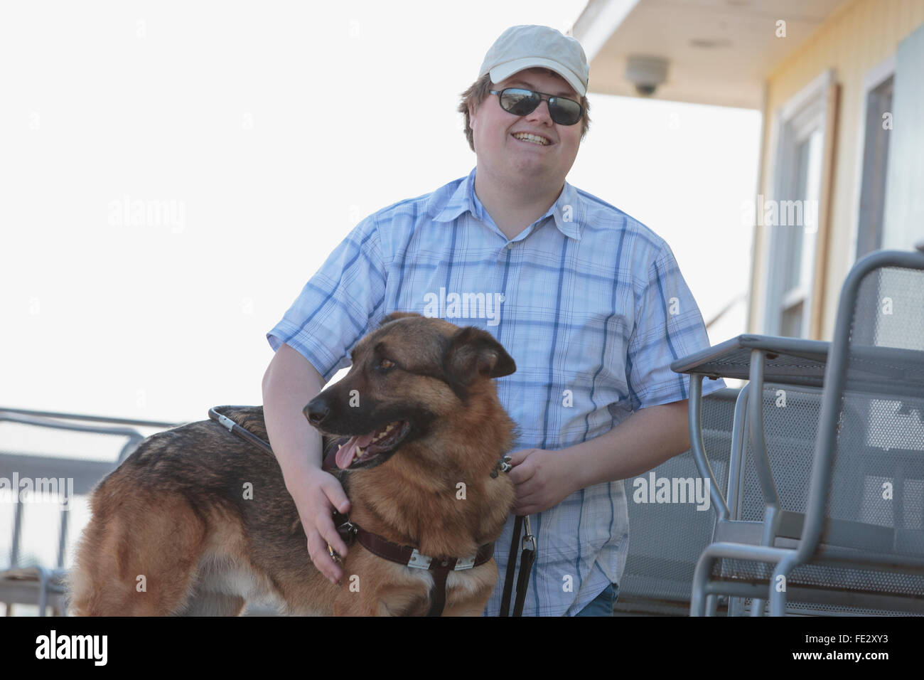 Blinder Mann mit seinem Servicehund in einem Straßencafé Stockfoto