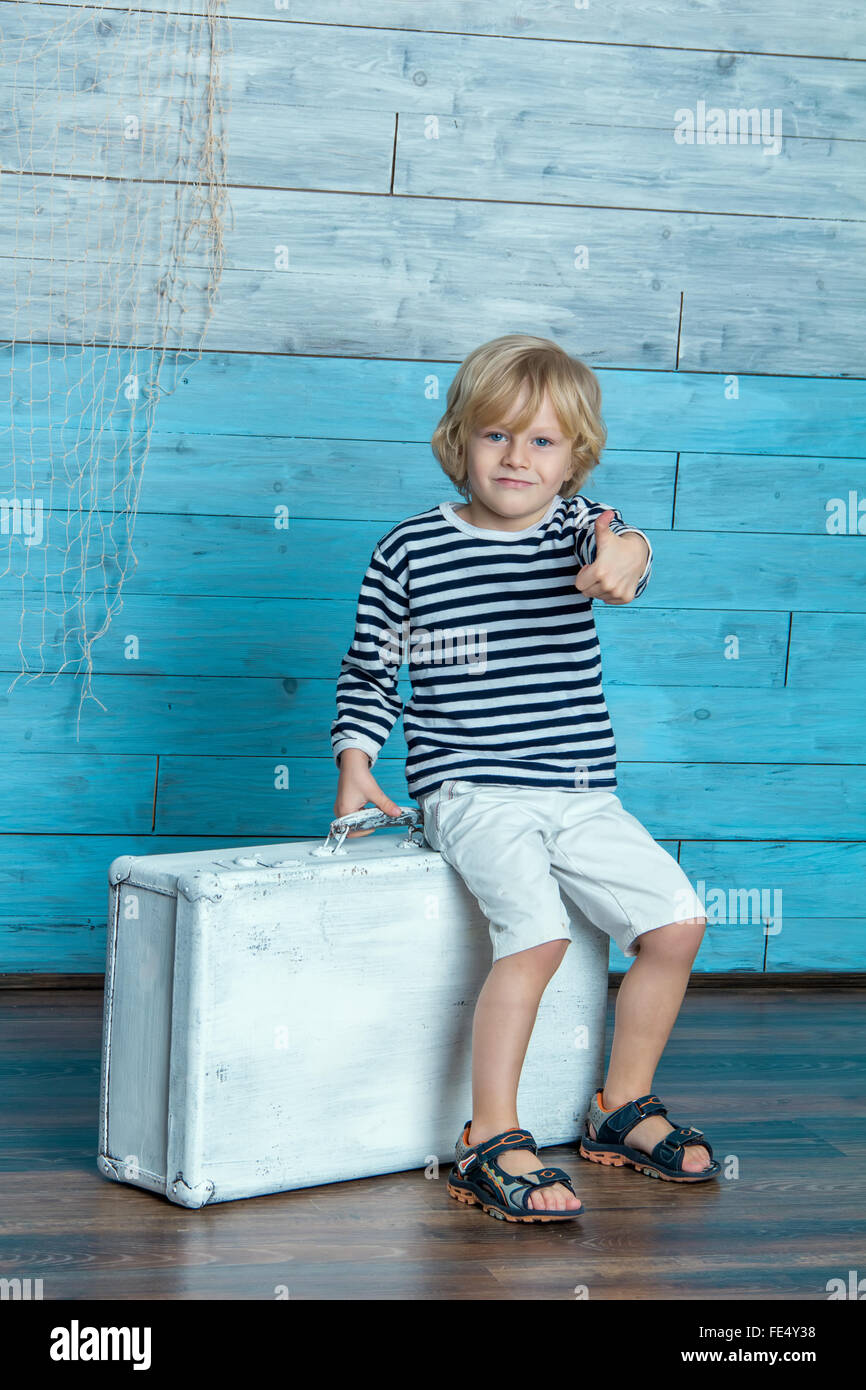 Kind sitzt auf einem Koffer Stockfoto