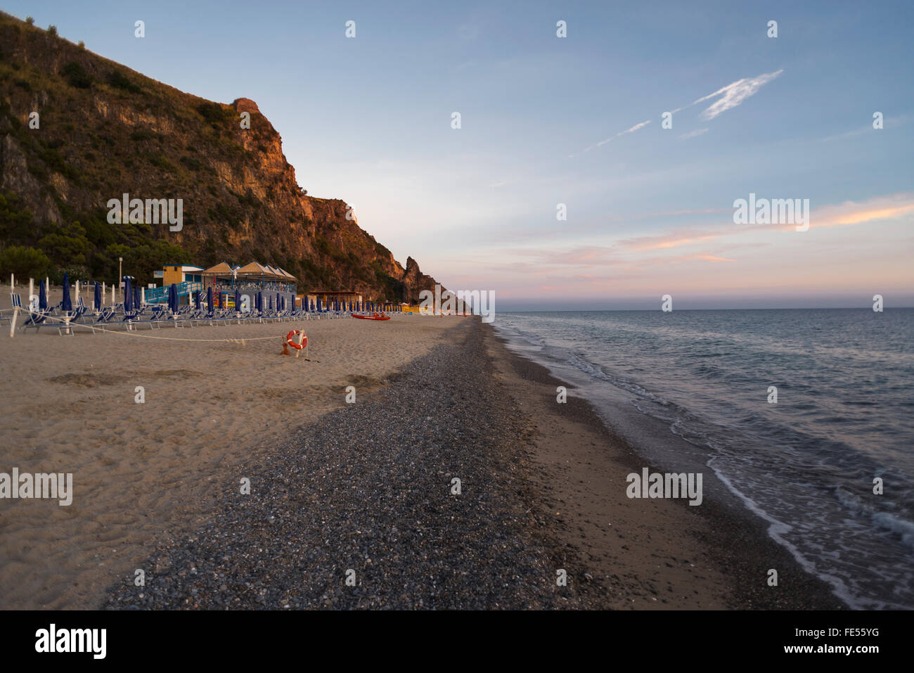 Liegestühle, Strandbäder und Sonnenschirme am Strand Mingardo an der Mittelmeerküste im Cilento im letzten Sonnenlicht, Kampanien, Italien Stockfoto