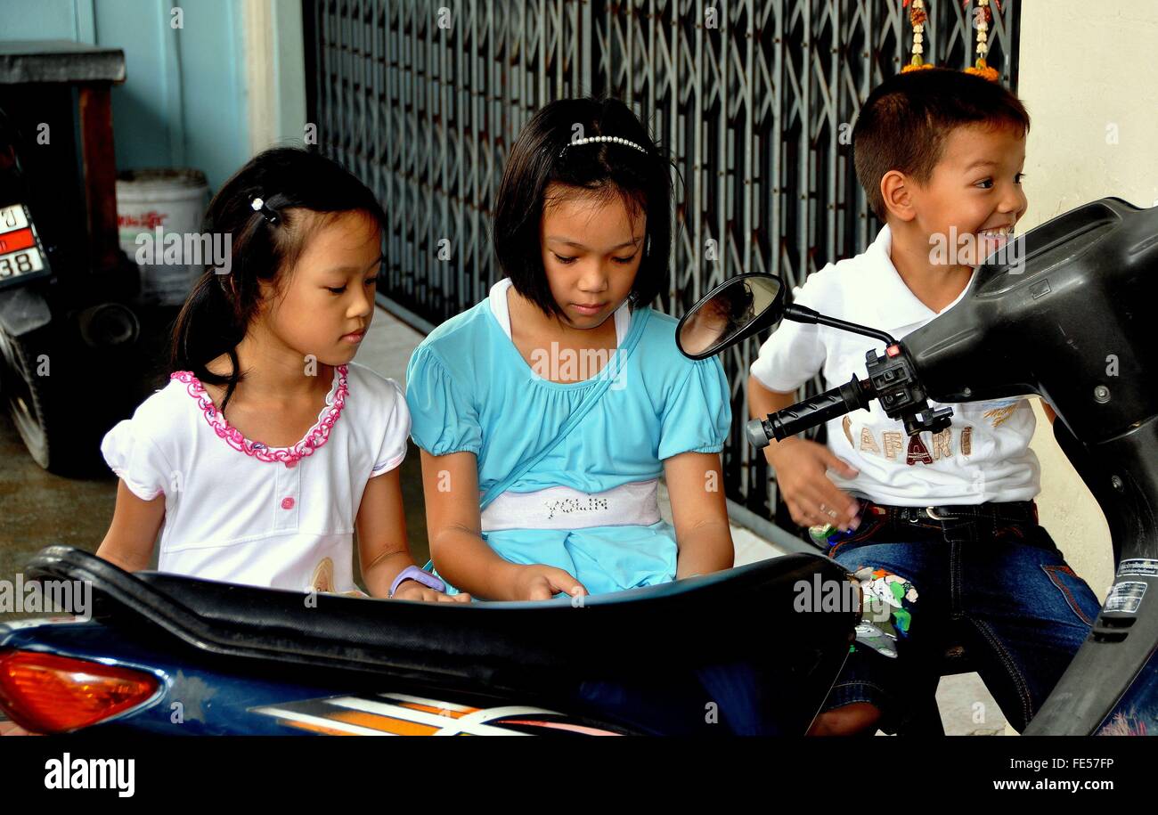 Stadt Phuket, Thailand: Drei kleine Thai Kinder spielen mit einer einer elektronischen Pad auf Krabi Road Stockfoto