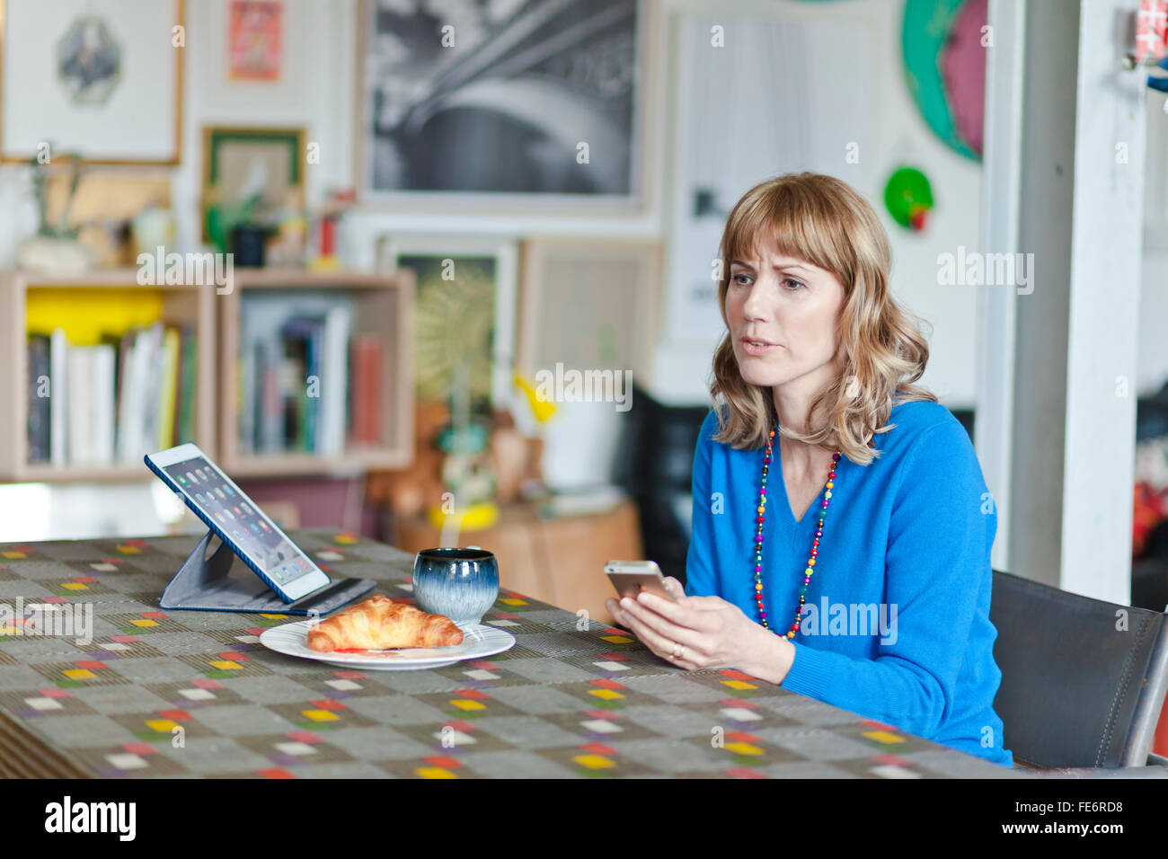 Frau verwirrt an einem Tisch im Wohnzimmer. Stockfoto