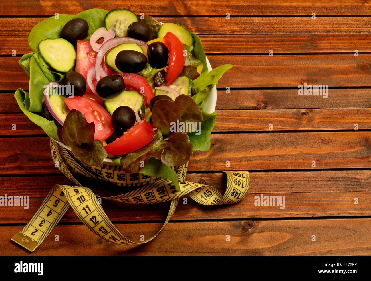 Schale mit Gemüsesalat und Zentimeter auf Holztisch Stockfoto