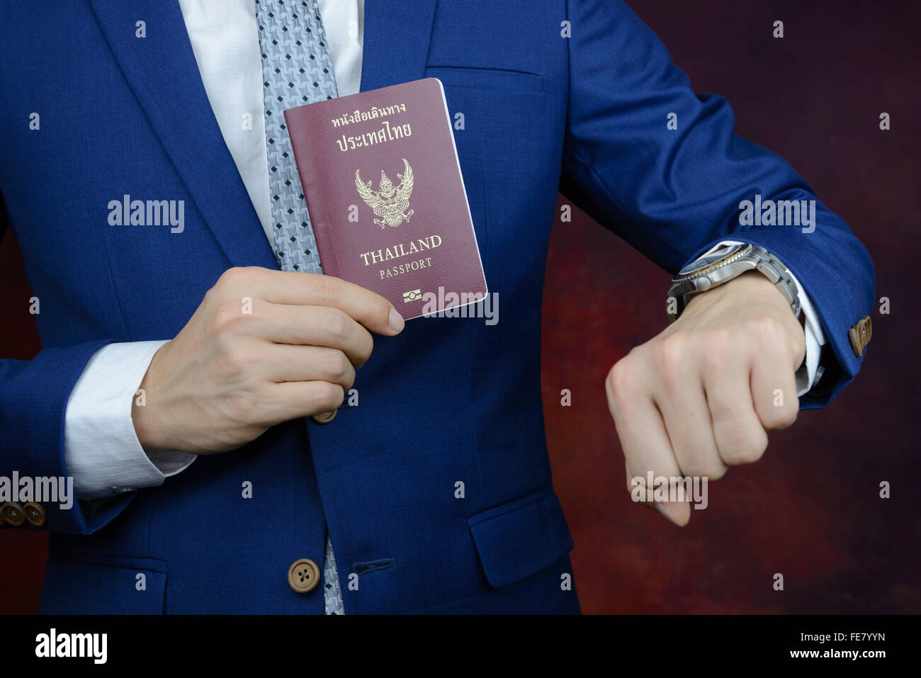 Kaufmann im blauen Anzug Überprüfung Zeit auf Uhr, zeigt Pass Stockfoto