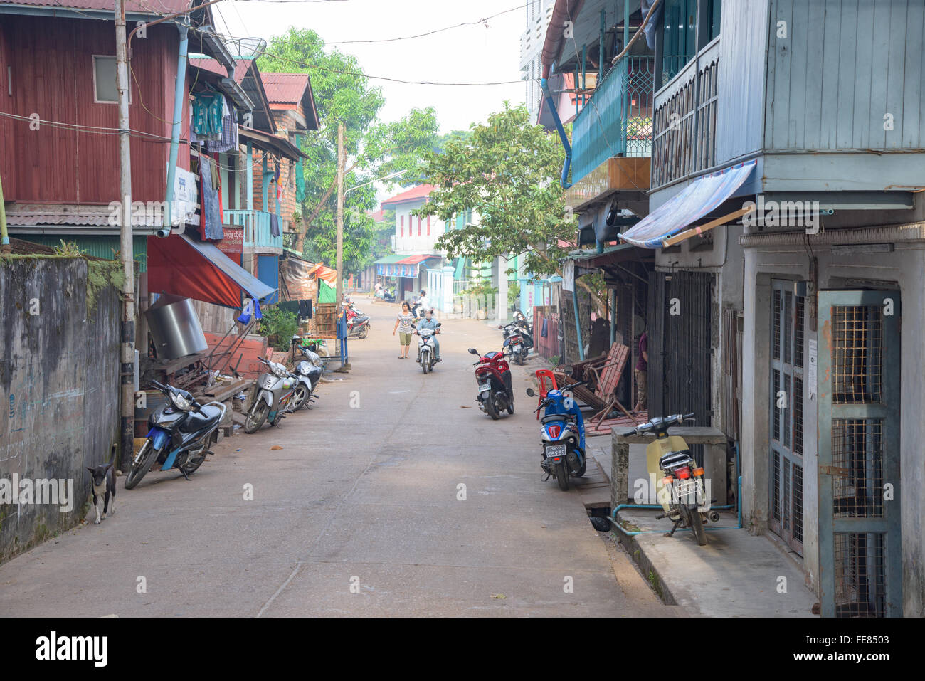 Straße mit Anwohnern und Motorräder im Wohngebiet im Myeik, eine Stadt im südlichen Myanmar. Stockfoto