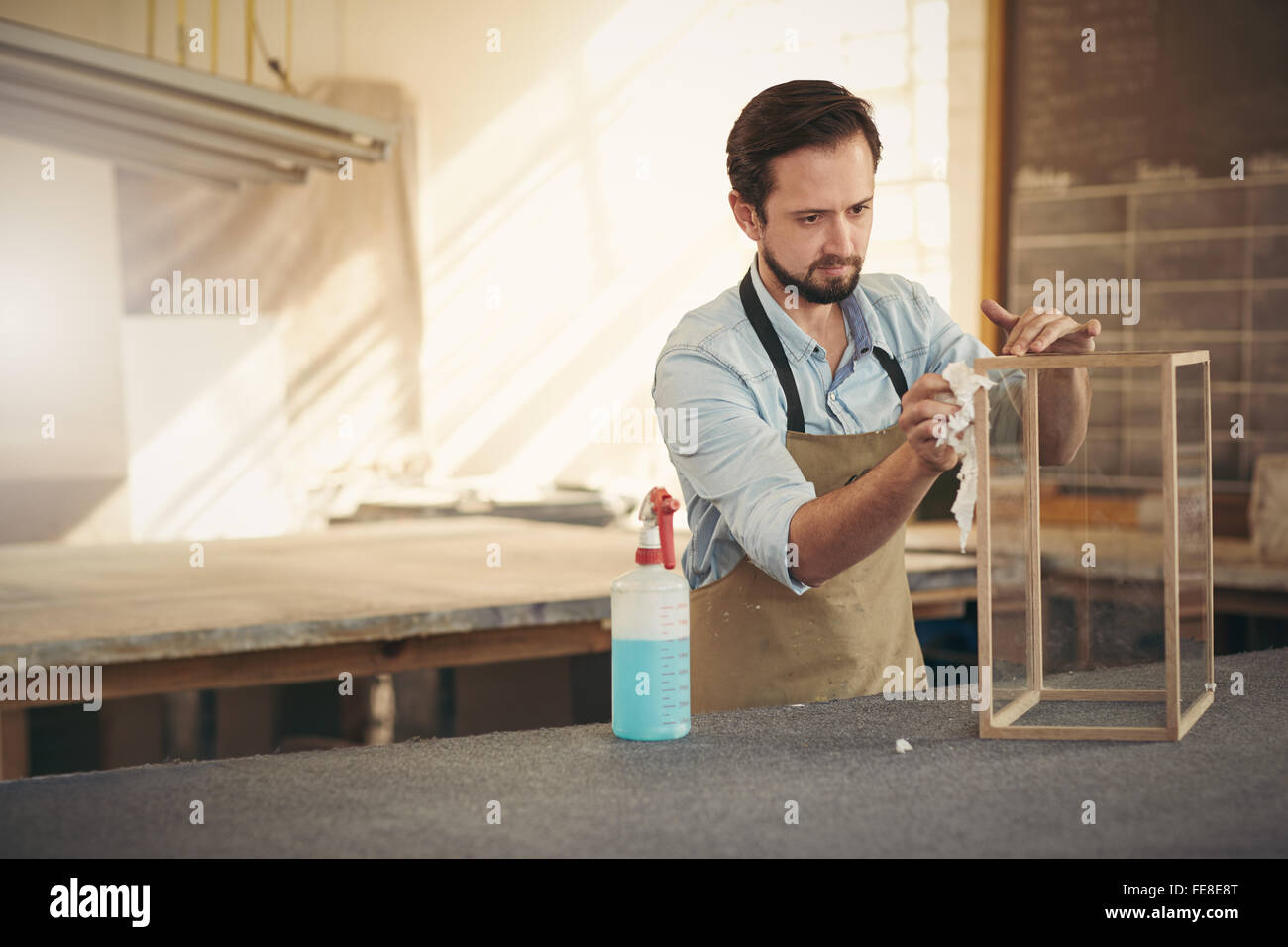 Handwerker-Designer, die Konzentration während der Anwendung den letzten Schliff für ein Projekt in seiner Werkstatt für Holzarbeiten Stockfoto