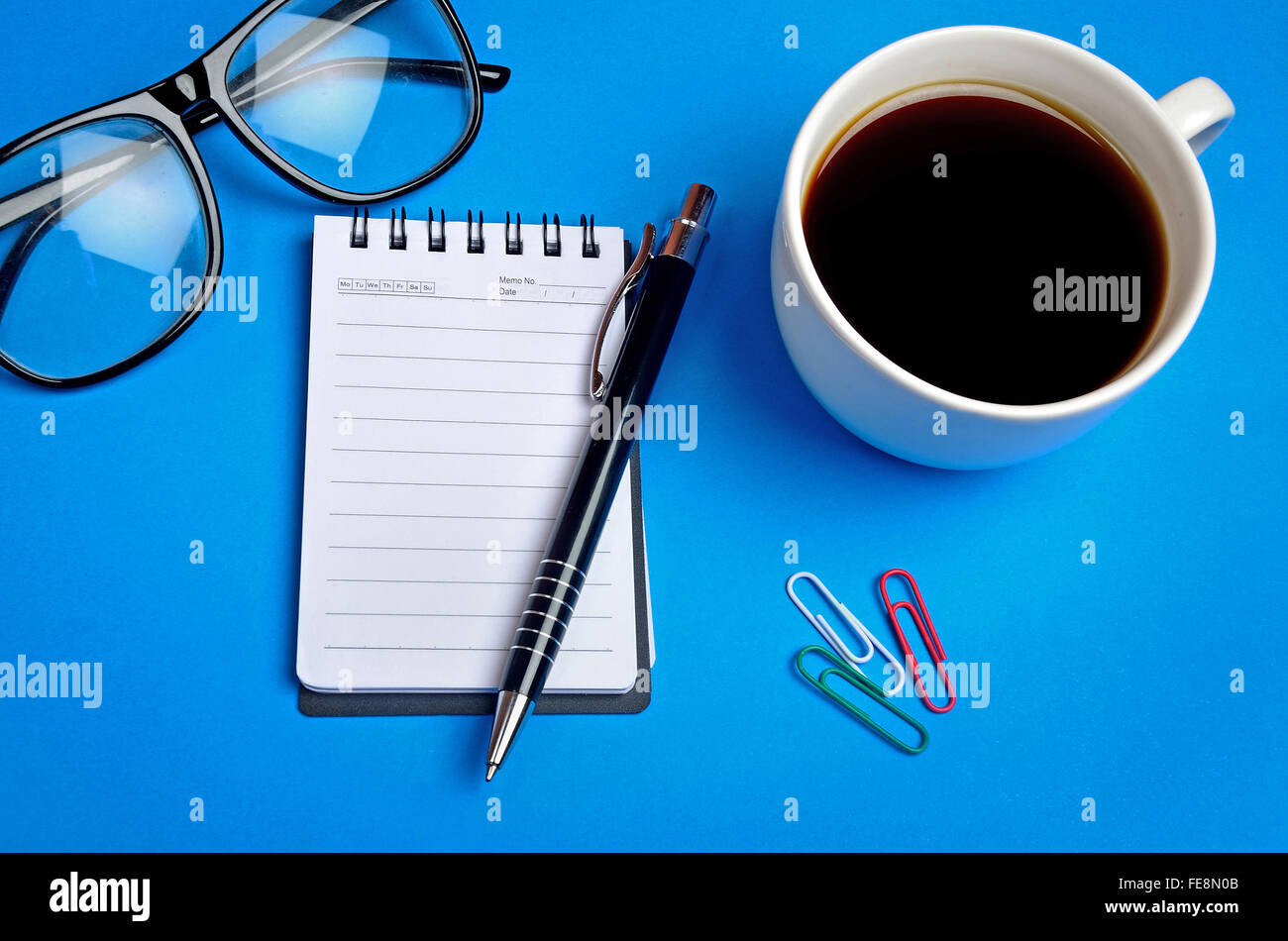 Notizblock mit Kaffeetasse auf Hintergrund Stockfoto