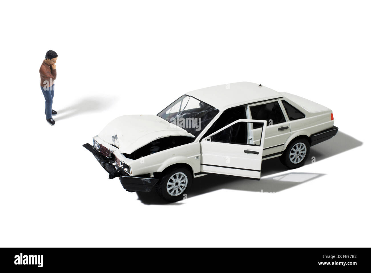 Spielzeug Man Looking at zerstörten Auto auf weißem Hintergrund Stockfoto