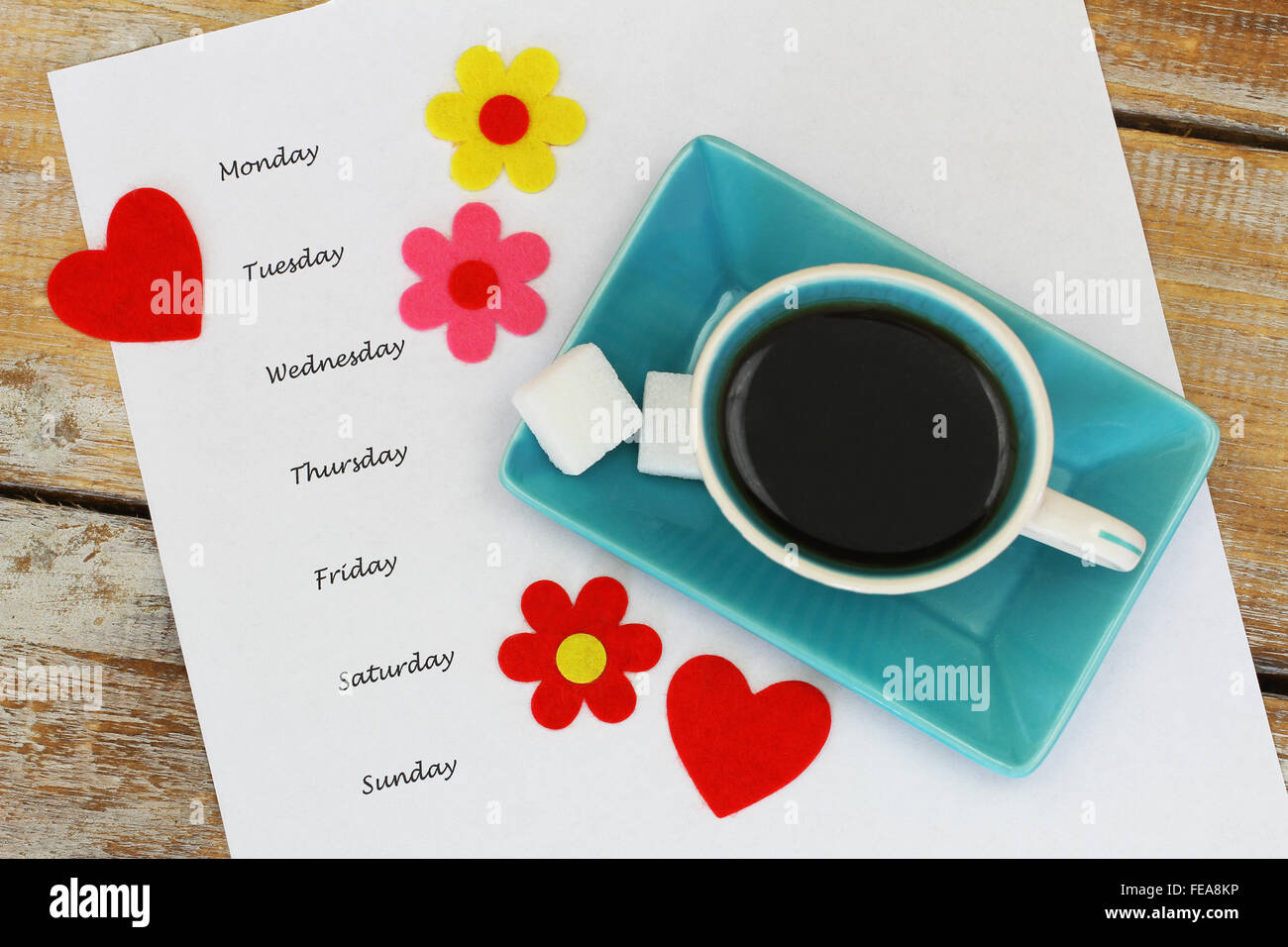 Wochentage auf weißes Blatt Papier mit Tasse Kaffee, bunten Blumen und roten Herzen geschrieben Stockfoto