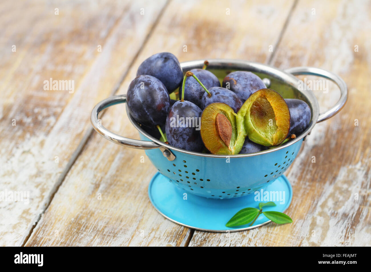 Saftige Pflaumen in blau Sieb auf rustikalen Holzoberfläche Stockfoto