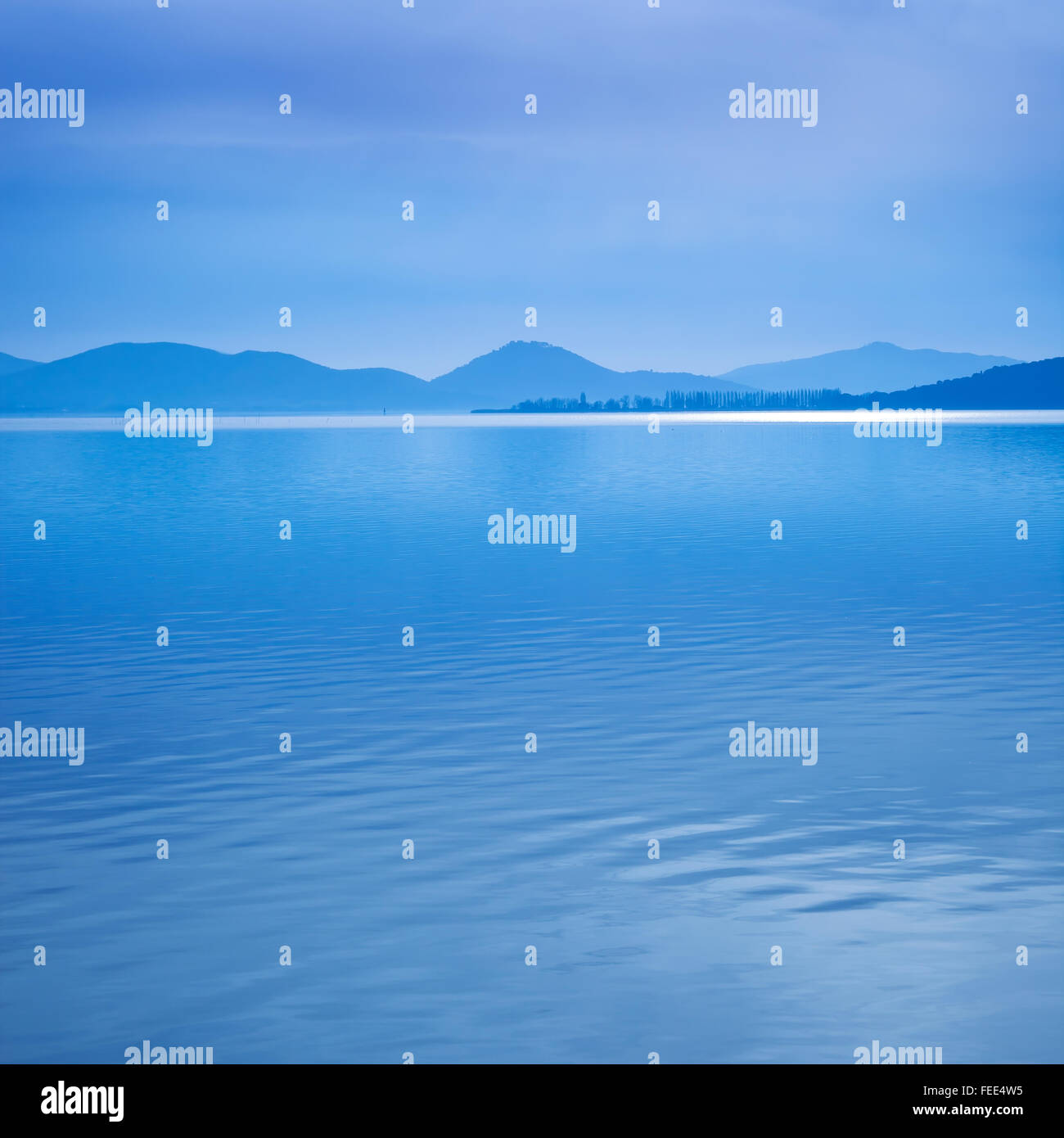 Wasseroberfläche in einem blauen Morgen am Trasimeno See, Umbrien Italien. Hügel im Hintergrund. Stockfoto