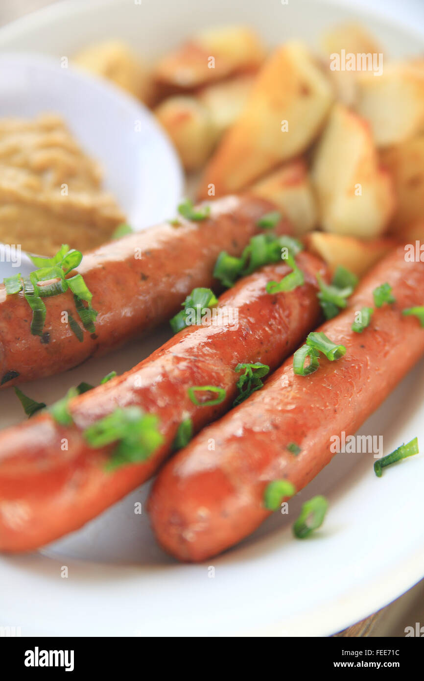 Würstchen mit gehackten Frühlingszwiebeln und Bratkartoffeln mit Senf Stockfoto