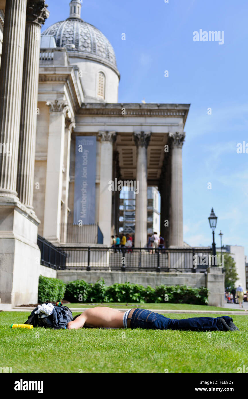 Ein junger Mann Sonnenbaden vor der National Gallery am Trafalgar Square in London, Vereinigtes Königreich. Stockfoto