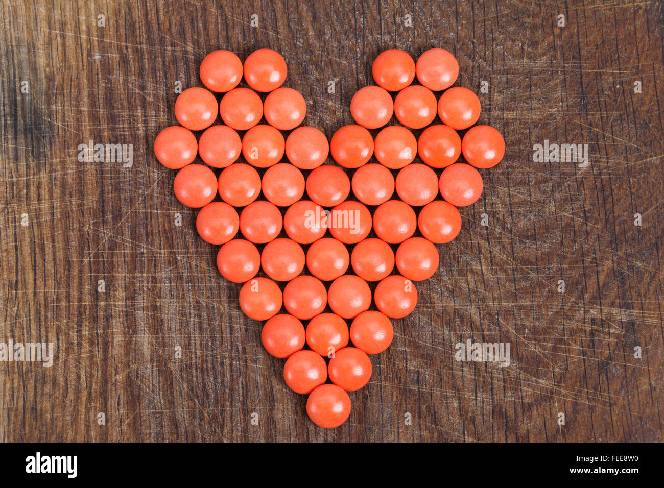 Rotes Herz mit Vitaminen auf Holzbrett. Stockfoto