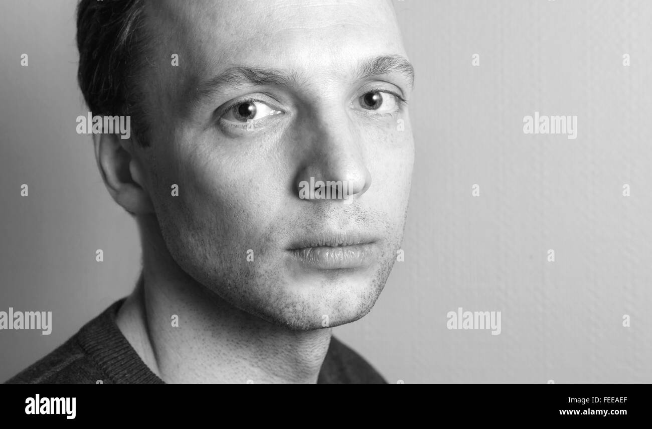 Ernsthafte kaukasischen Jüngling, close-up Studioportrait über graue Wand Hintergrund, schwarz / weiß Foto Stockfoto