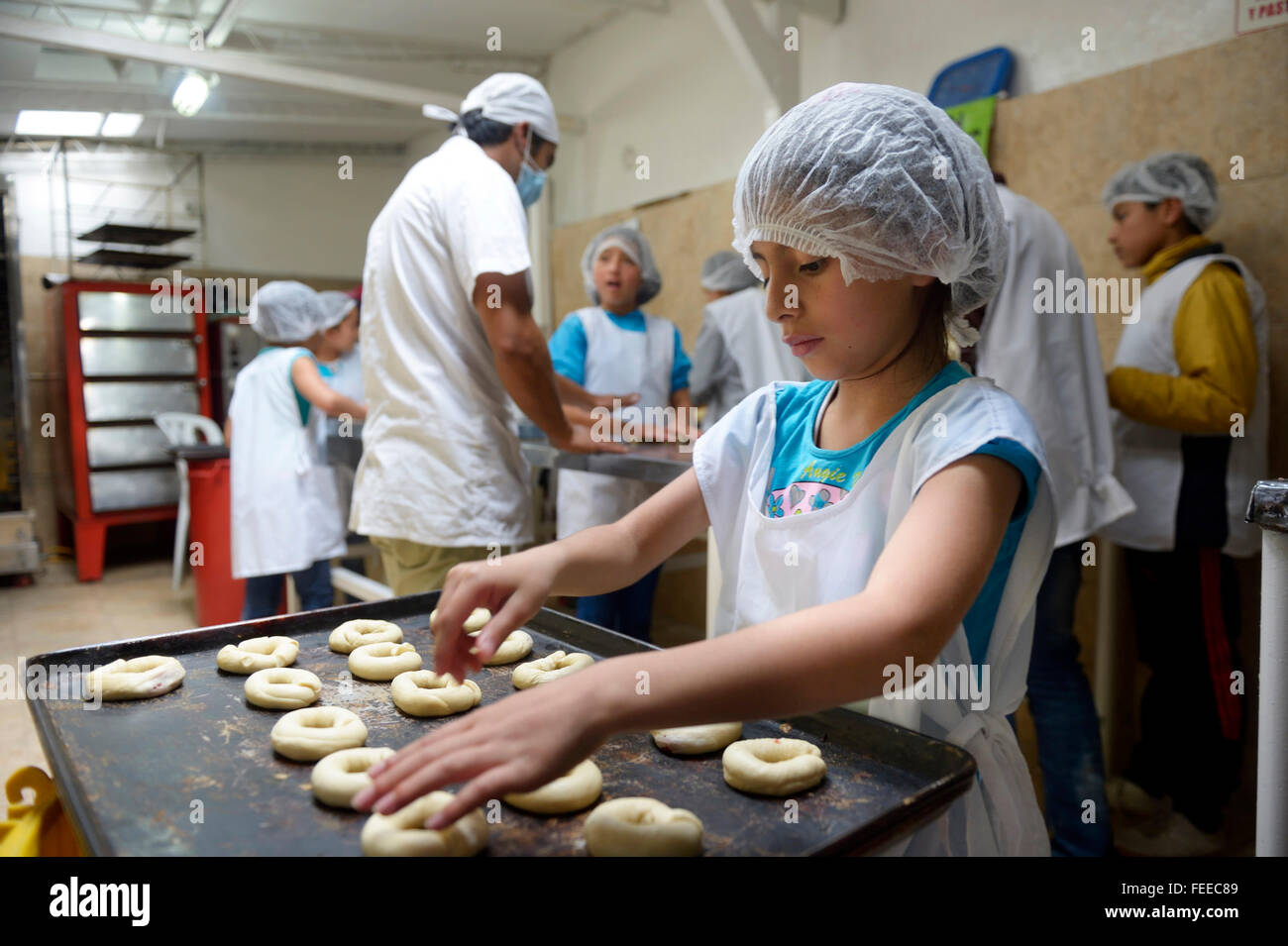 Mädchen Platzierung Rohteig Ringen auf Tablett, Bäckerei, berufliche Ausbildung, Creciendo Unidos Sozialprojekt, Villa Javier, Bogotá Stockfoto