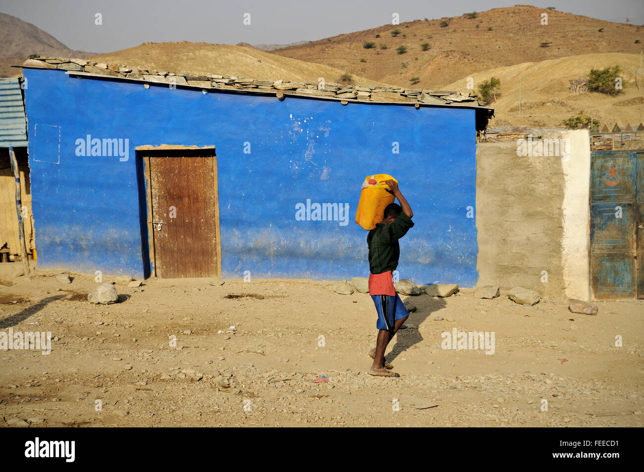 Mann mit einem Kunststoff kann auf seiner Schulter in das Dorf Berhale, Afar-Region, Äthiopien Stockfoto