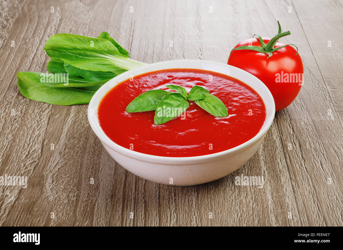 Frische Tomatensuppe in Schüssel auf hölzernen Hintergrund weiß Stockfoto