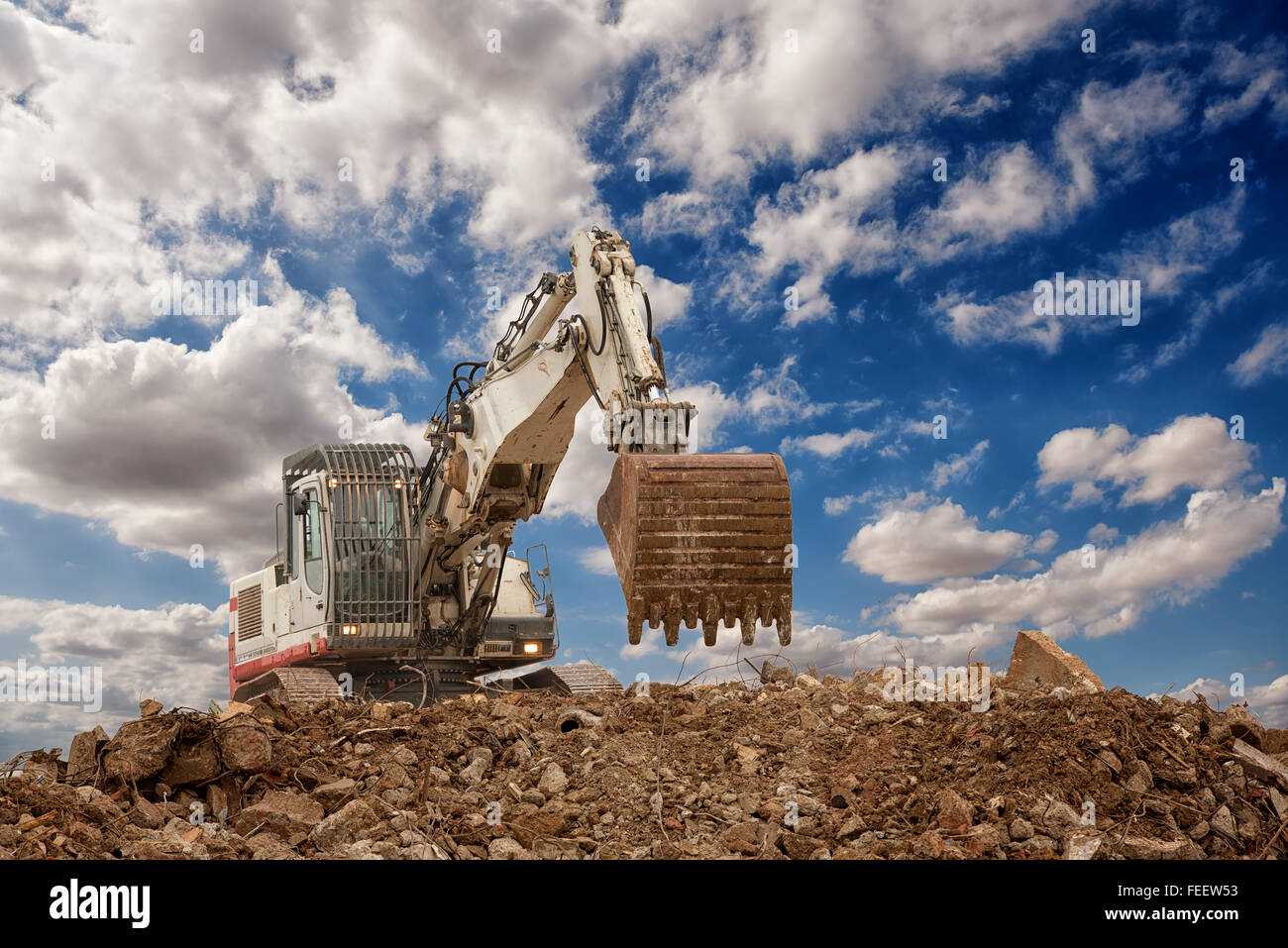 Bagger mit Schaufel am Kiese blau bewölktem Himmelshintergrund Stockfoto
