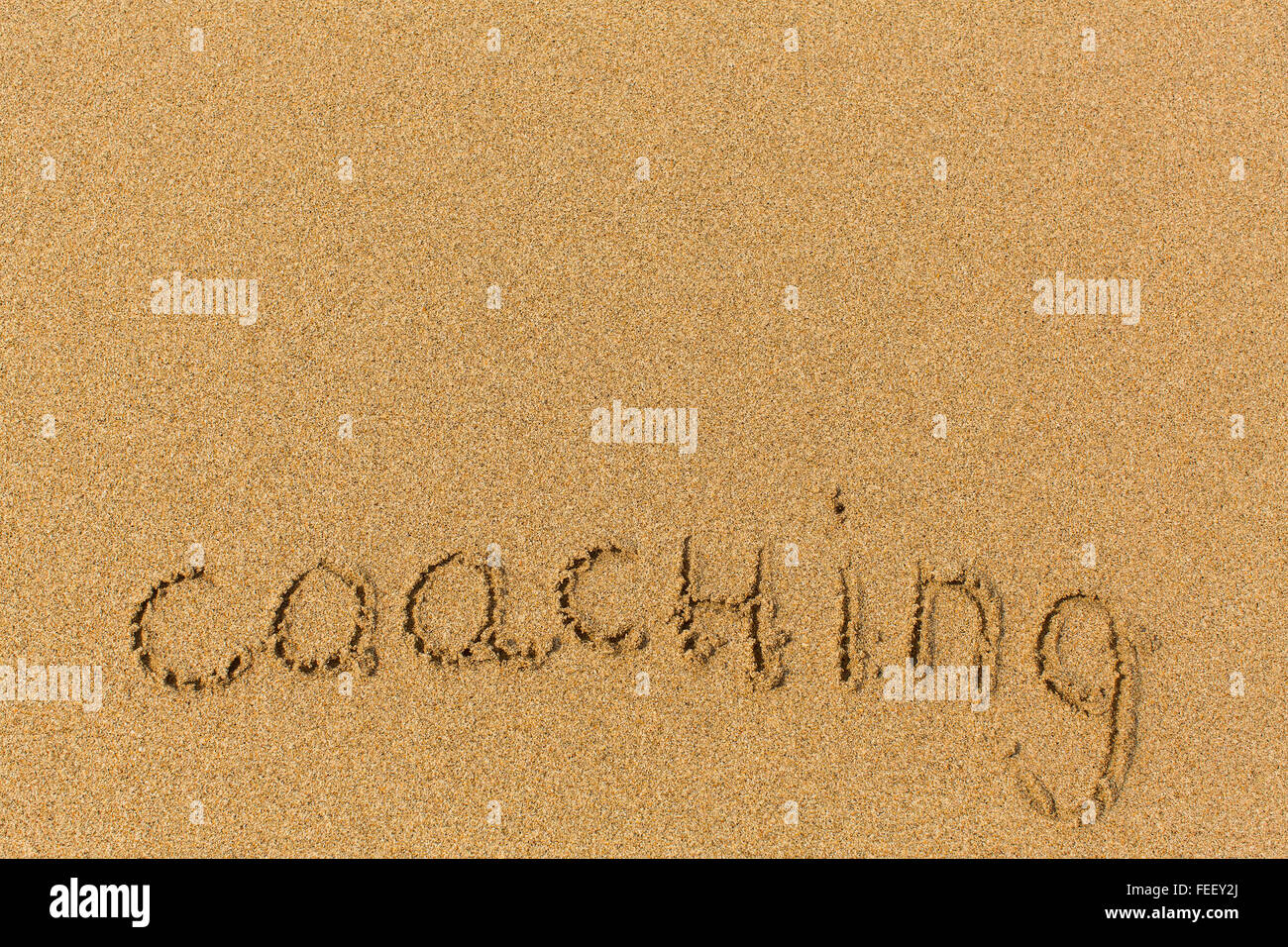 Coaching - Wort gezeichnet am Sandstrand. Hintergrund, Beschaffenheit des Sandes. Stockfoto