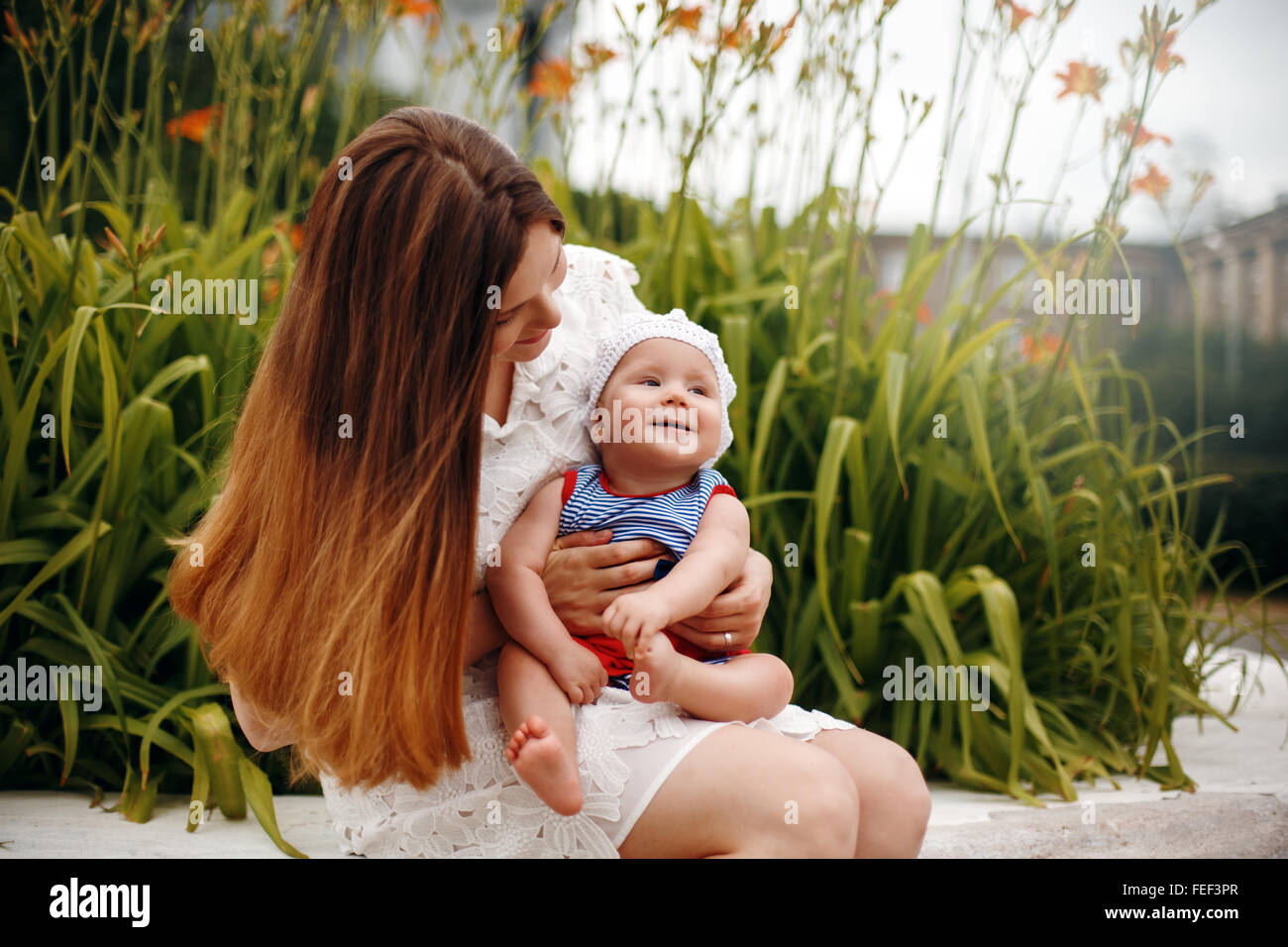 Niedliche glücklich Kleinkind auf liebevolle Mutter Knien sitzen und Lächeln auf den Lippen. Familienspaß. Selektiven Fokus. Stockfoto