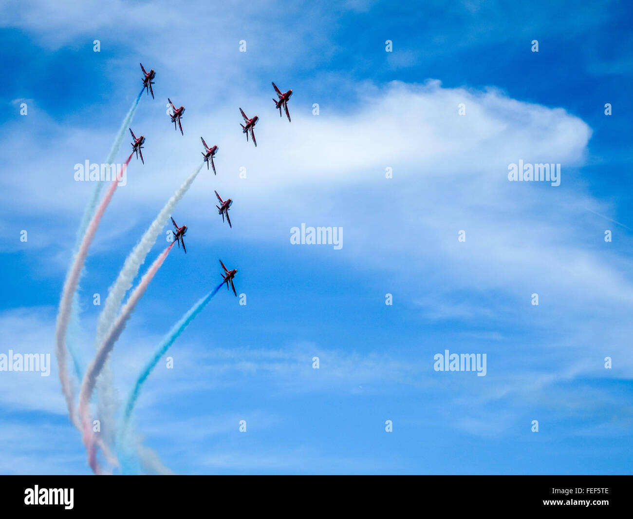 Die roten Pfeile fliegen in Formation mit rot, weiß, und blaue Rauch Wanderwege. Stockfoto