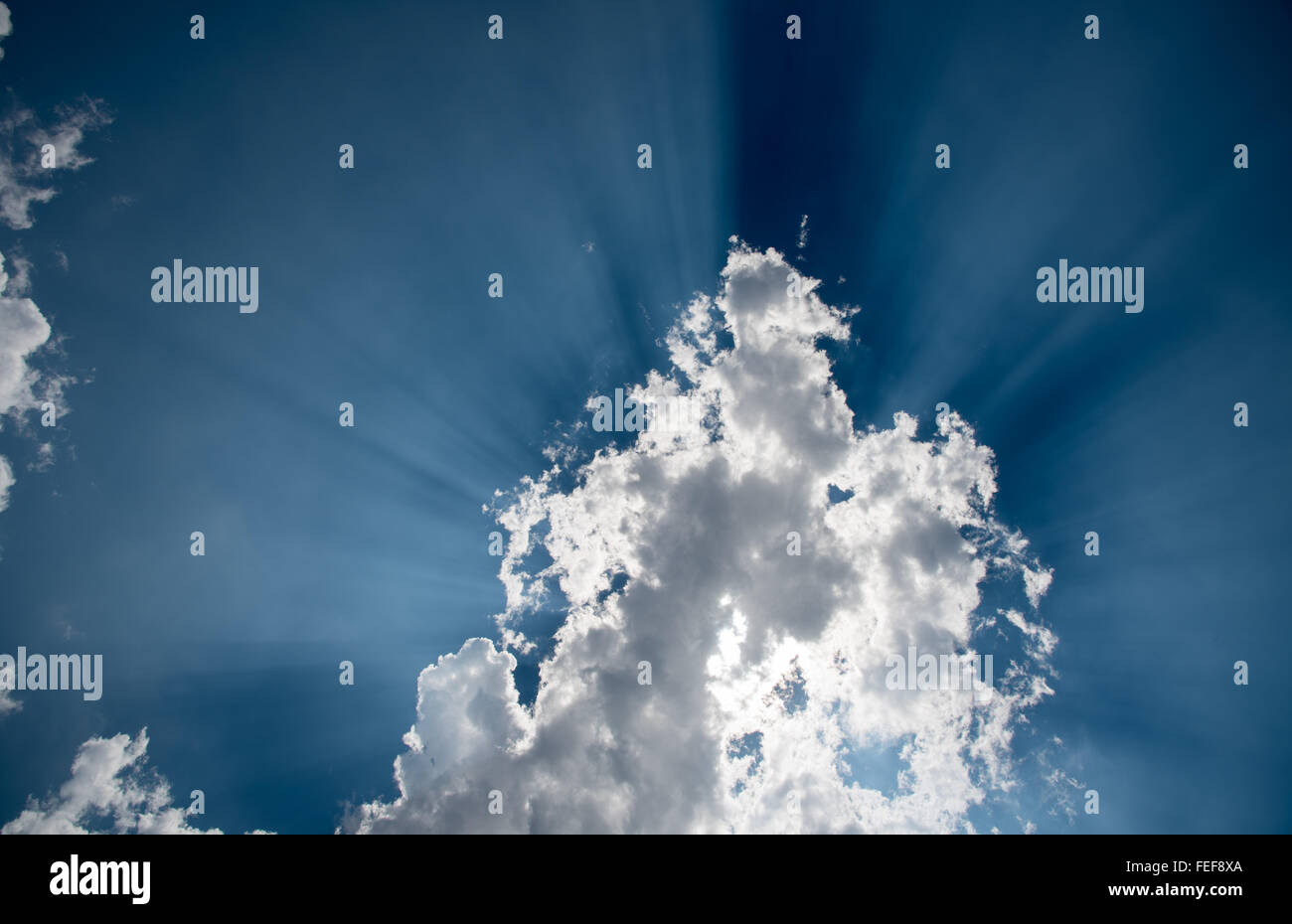 Sonnenstrahlen hinter weißen Cumulus-Wolken am blauen Himmel. Zeigen Sie ein neues Leben oder Himmel und Zukunft geboren. Stockfoto