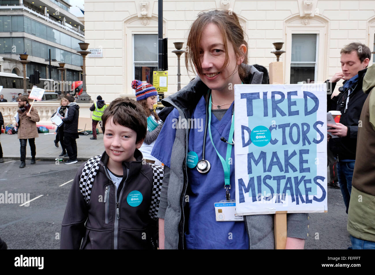 Eine weibliche junior Arzt mit ihrem Sohn, der ein Plakat lesen' Müde ärzte Fehler zu machen Stockfoto