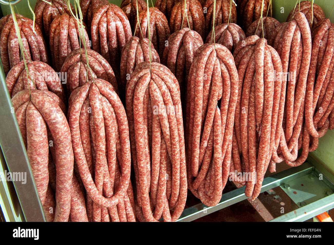 Verschiedene frisch hergestellte Würste hängen in einer Metzgerei Stockfoto