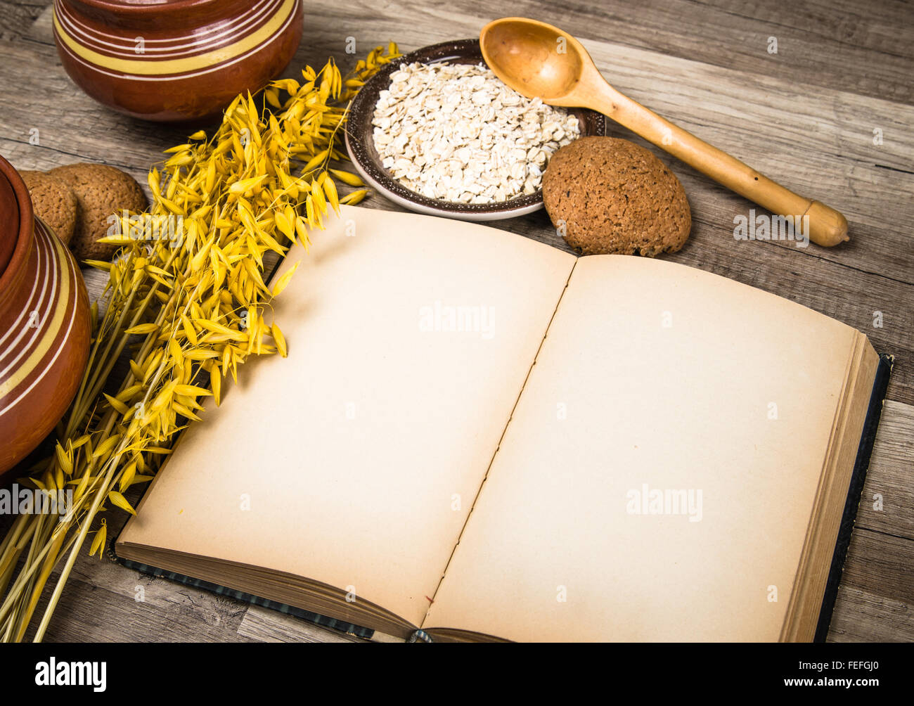 Haferflocken-Cookies und ein altes Rezeptbuch auf dem Küchentisch Stockfoto