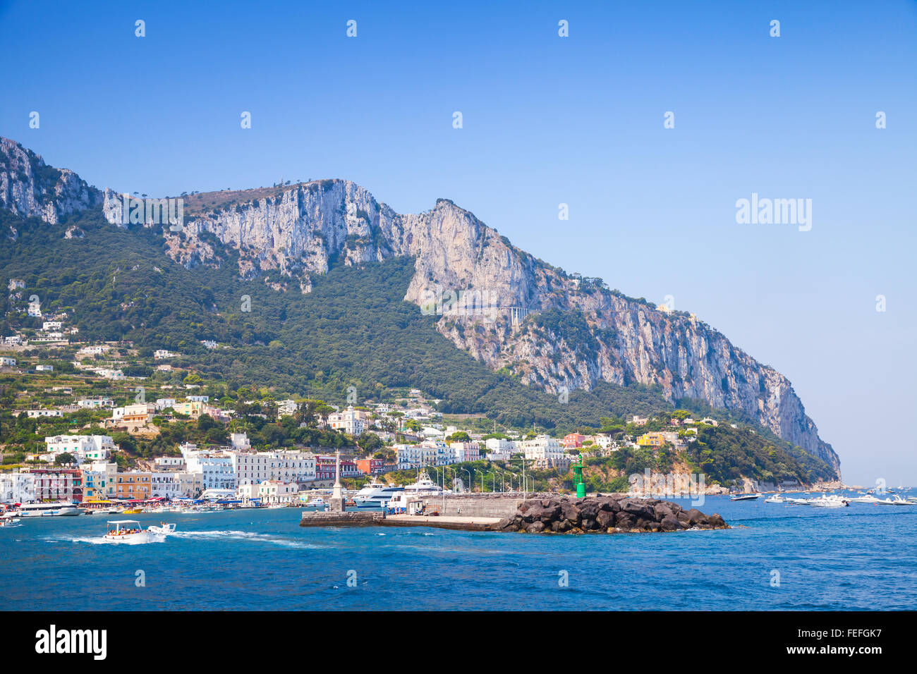Eingang des Capri Hafen, Italien. Boote fahren in der Nähe von Wellenbrecher mit grünen Leuchtturm Stockfoto