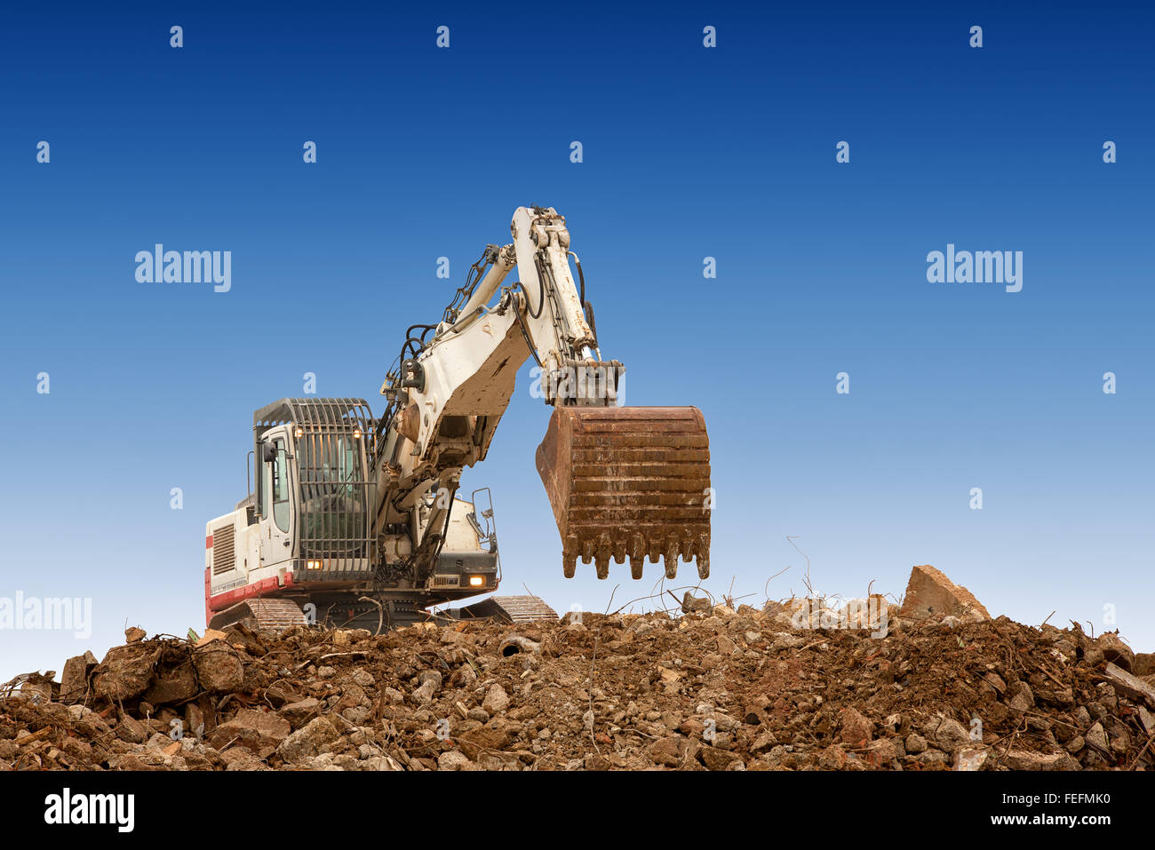 Bagger mit Schaufel am Kiese blauen Himmelshintergrund Stockfoto